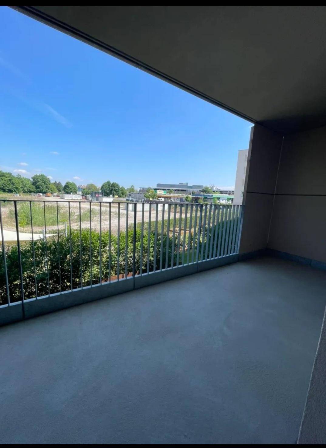 Balkon mit weitem Blick über eine offene Fläche und die städtische Umgebung.