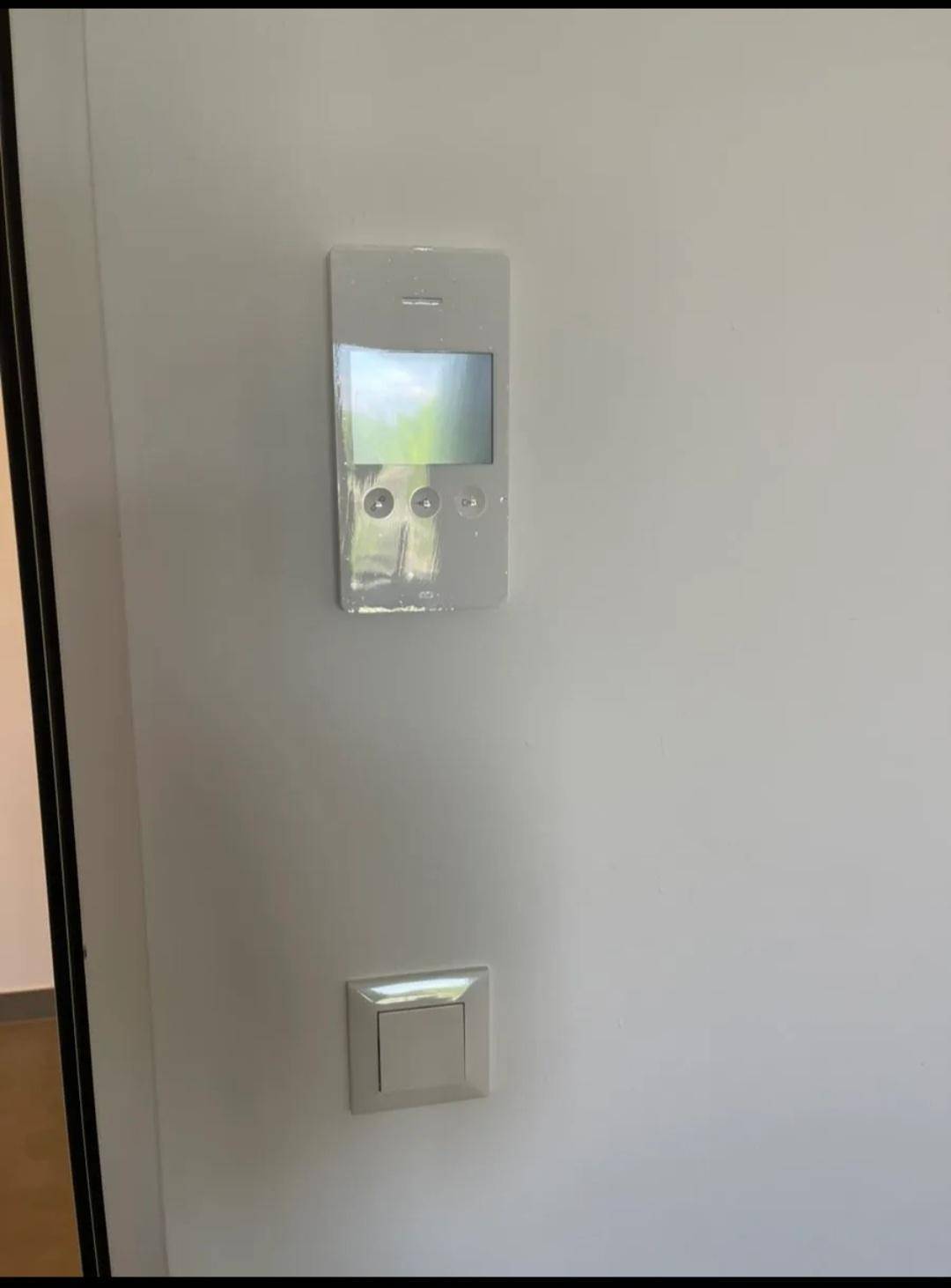 Gegensprechanlage und Lichtschalter an einer weißen Wand im Eingangsbereich.
