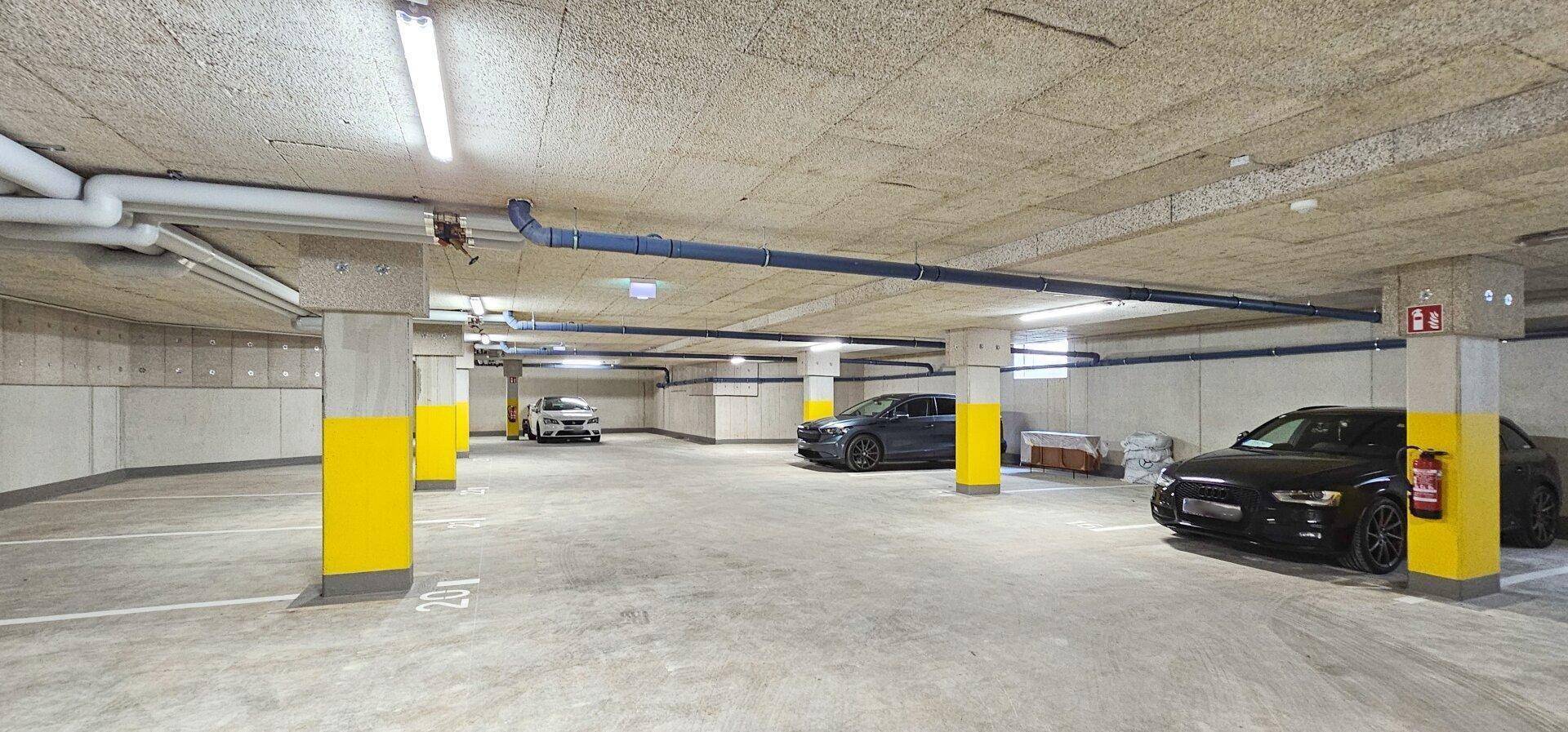 Geräumige Tiefgarage mit Betonpfeilern und markierten Parkplätzen für mehrere Fahrzeuge.
