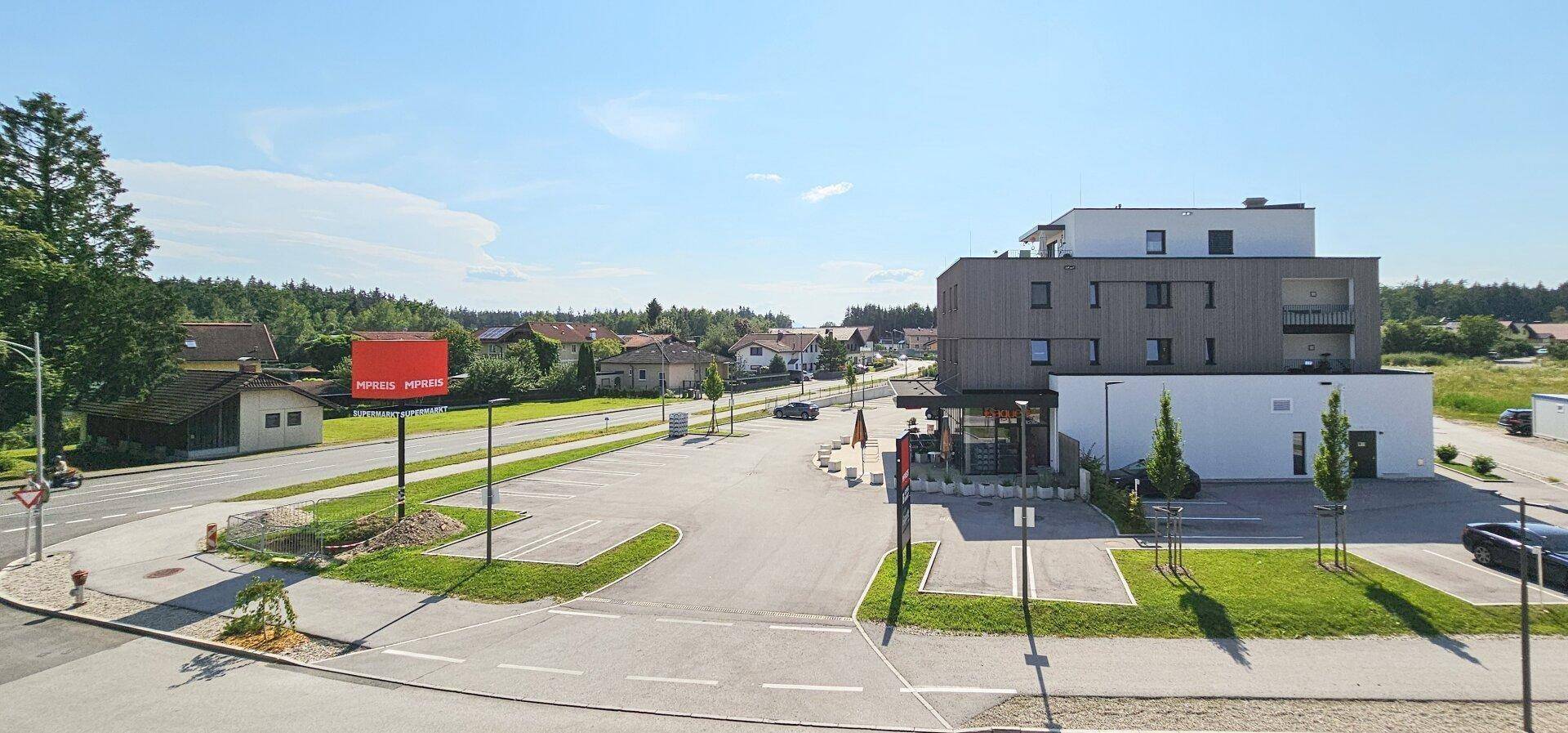 Übersicht über ein Gewerbegebiet mit modernem Gebäude, Parkplatz und umliegender Wohnbebauung.