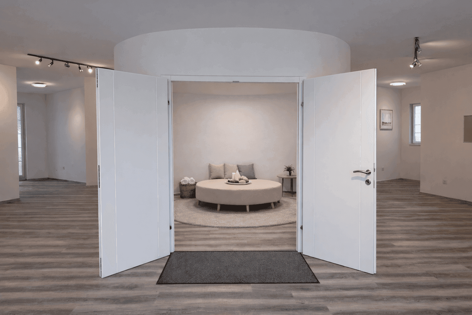Geräumiger Innenbereich mit offenstehenden Türen zu einem runden Lounge-Bereich und modernem Laminatboden.