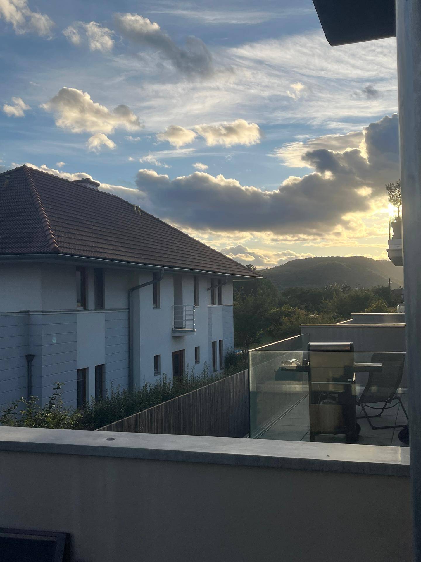Balkon mit Aussicht auf umliegende Häuser und eine malerische Berglandschaft im Hintergrund.