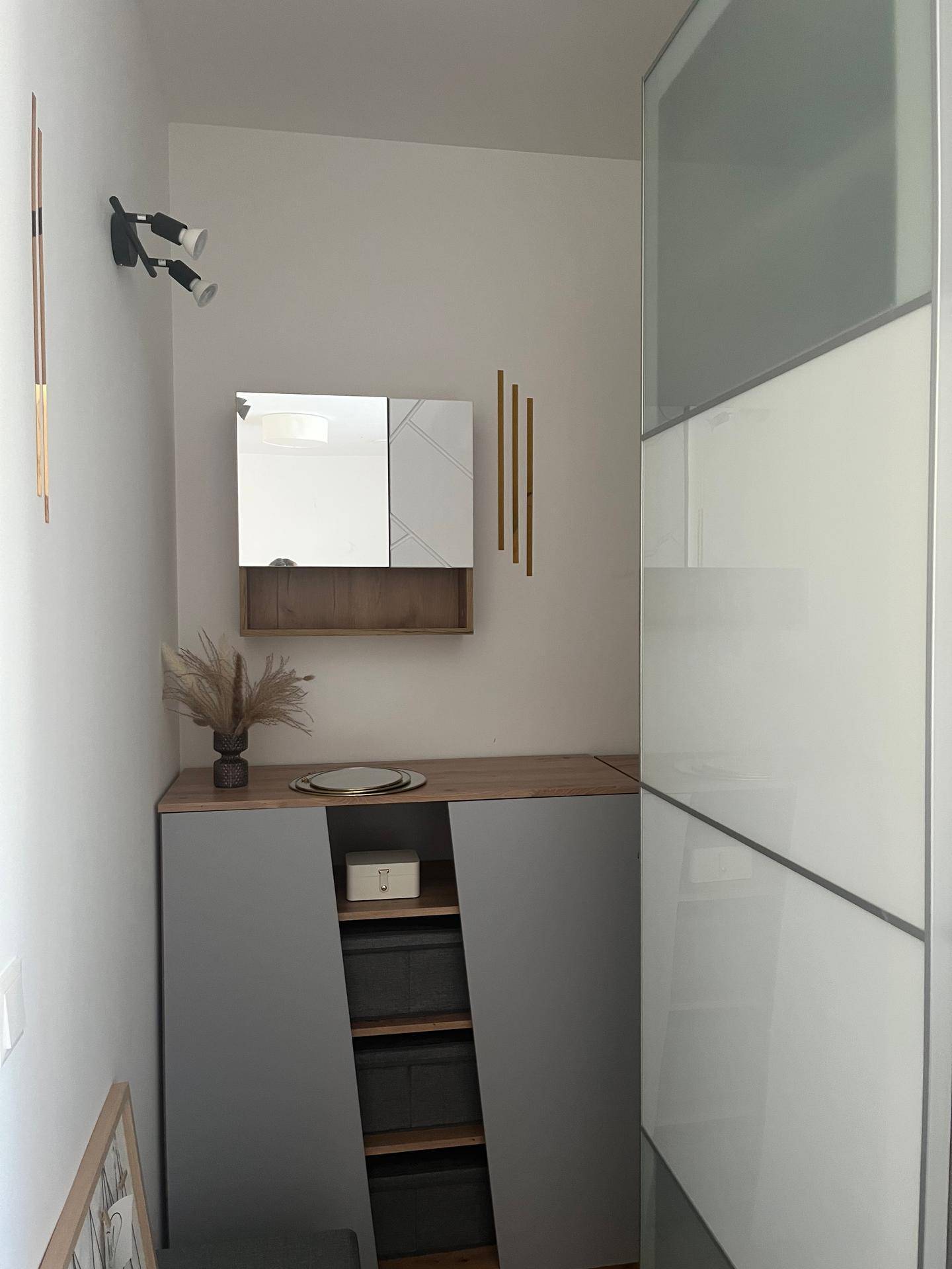 Moderner Eingangsbereich mit Schuhschrank, Spiegel und dekorativen Wandleuchten, funktional gestaltet.
