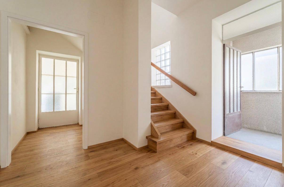 Renovierter Flurbereich mit Holztreppe und Parkettboden, hell und einladend gestaltet.
