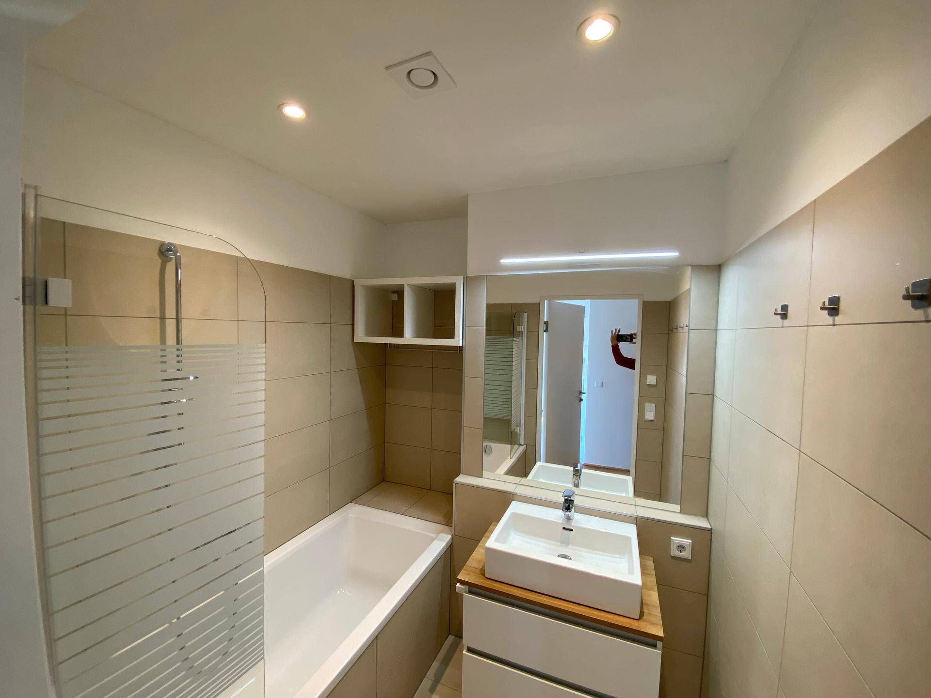 Modernes Badezimmer mit Badewanne, Dusche und großem Spiegel über dem Waschbecken.