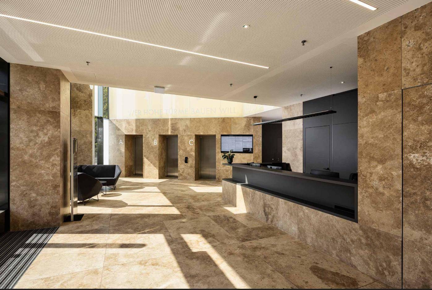 Elegante Lobby mit Natursteinboden, Aufzügen und modernem Empfangsbereich.