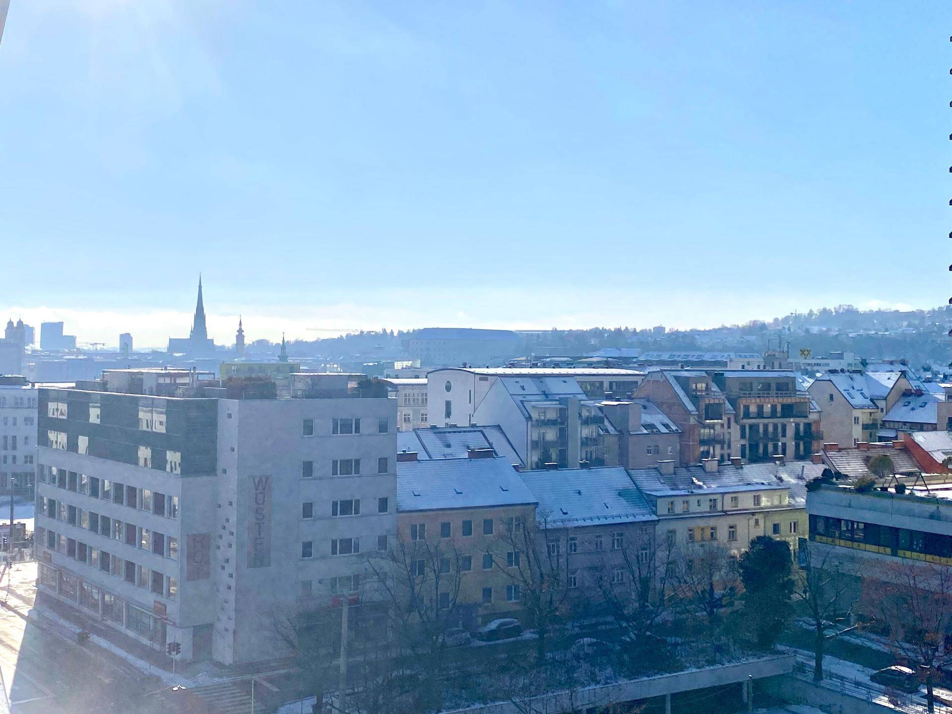 Weitläufiger Blick über die verschneite Stadt mit markanten Gebäuden und blauem Himmel.