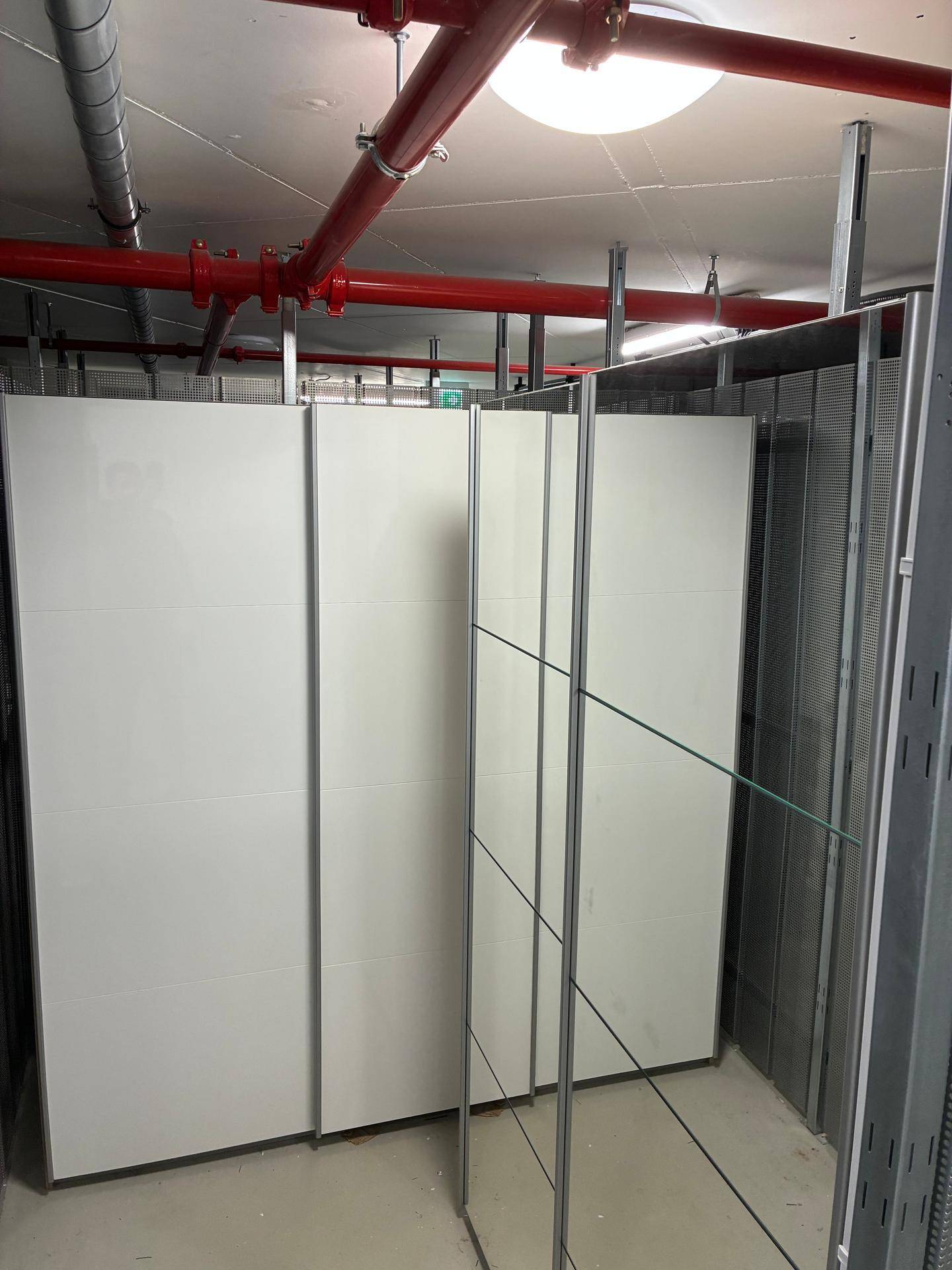 Lagerraum mit weißen Trennwänden und Metallregalen für organisierte Aufbewahrung.