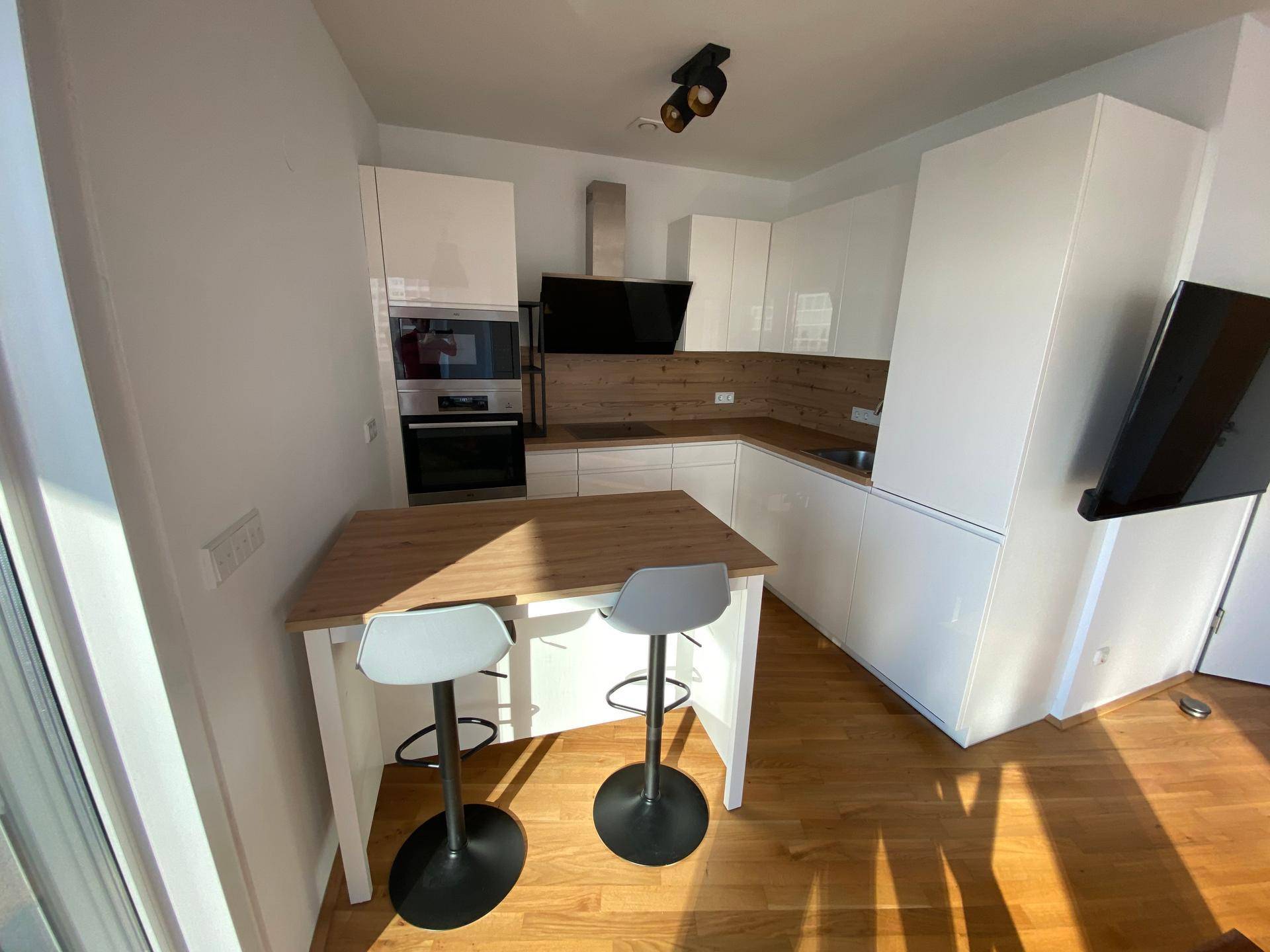 Moderne Einbauküche mit weißen Hochglanzfronten, integrierten Geräten und Frühstücksbar.