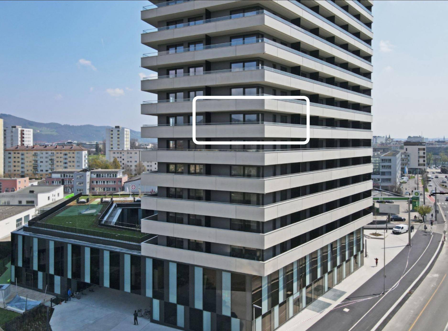 Moderne Hochhausfassade mit vielen Balkonen und klaren Linien in städtischer Umgebung.