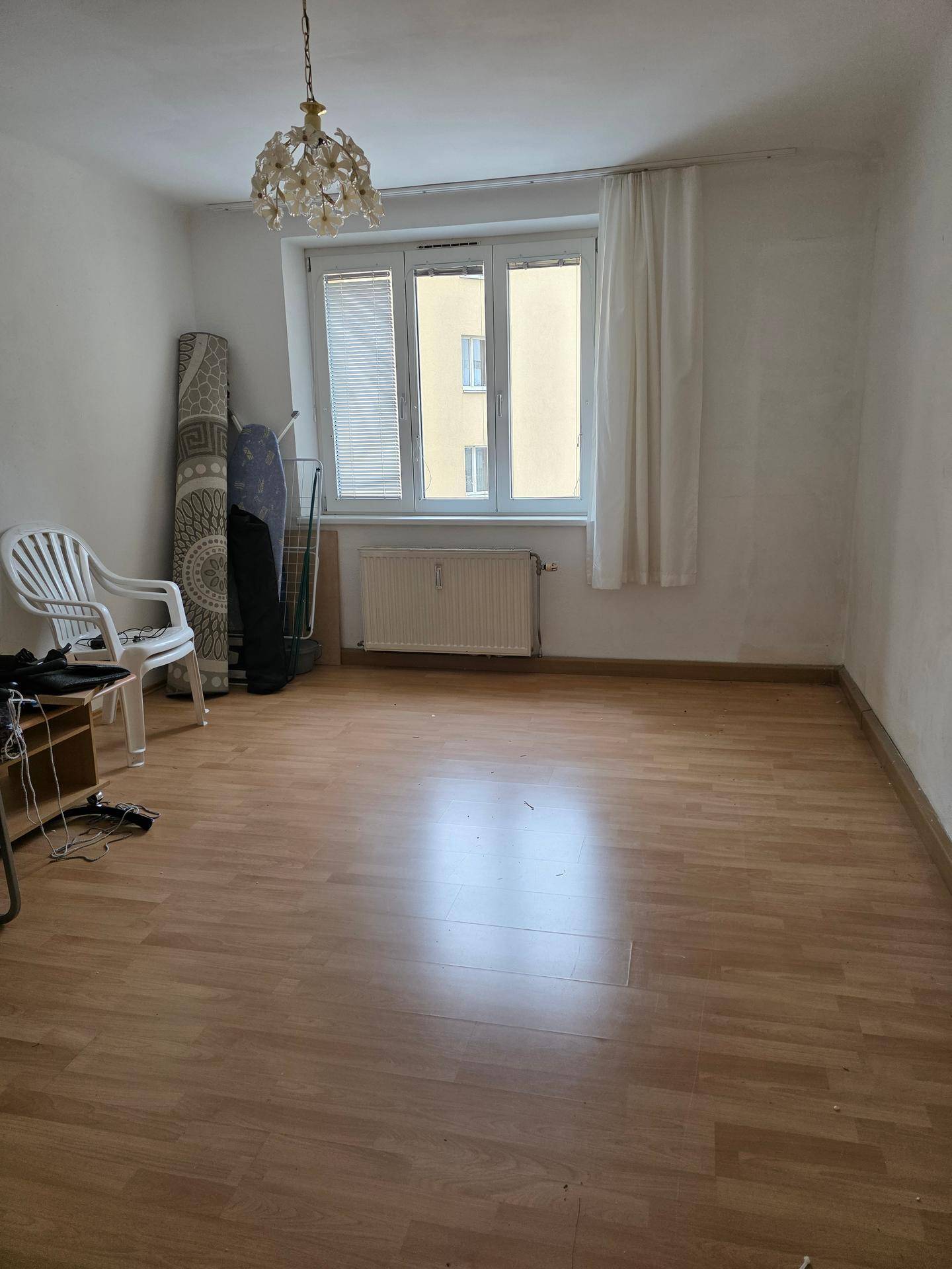 Geräumiger Wohnbereich mit Laminatboden, Fenster und Deckenleuchte, ideal für neue Einrichtung.