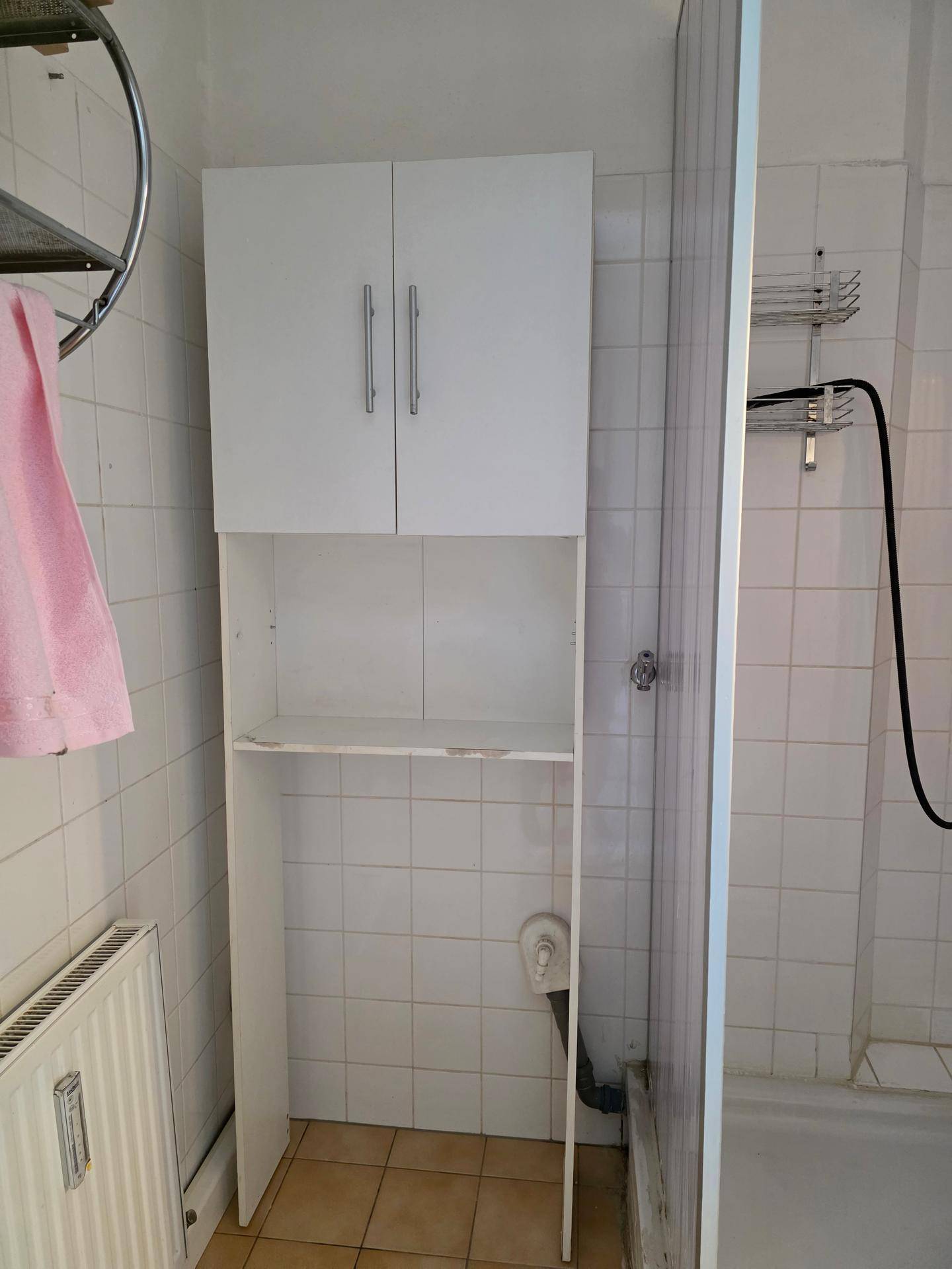 Helles Badezimmer mit Heizkörper, Waschbecken und praktischem Hochschrank für Stauraum.
