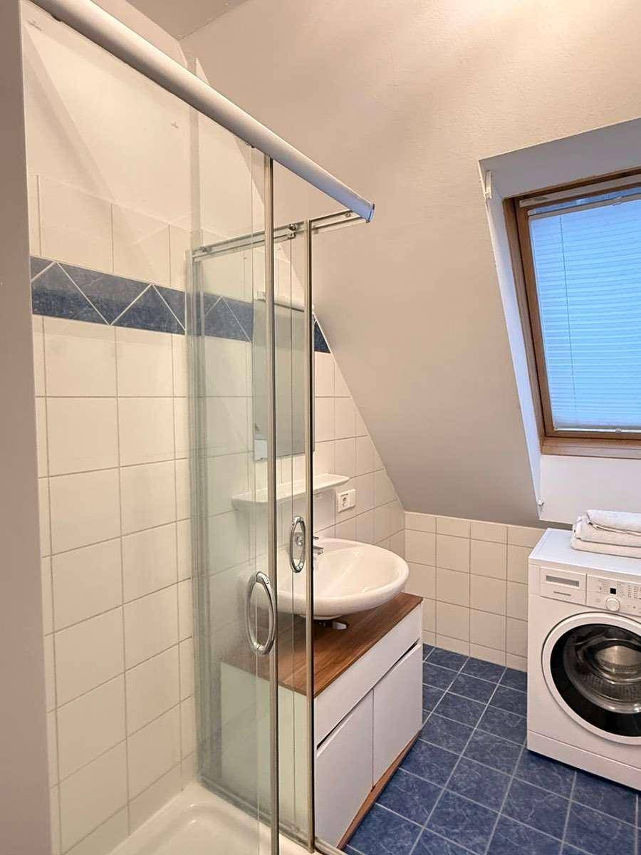 Modernes Badezimmer mit Dusche, Waschmaschine und Dachfenster unter der Schräge.