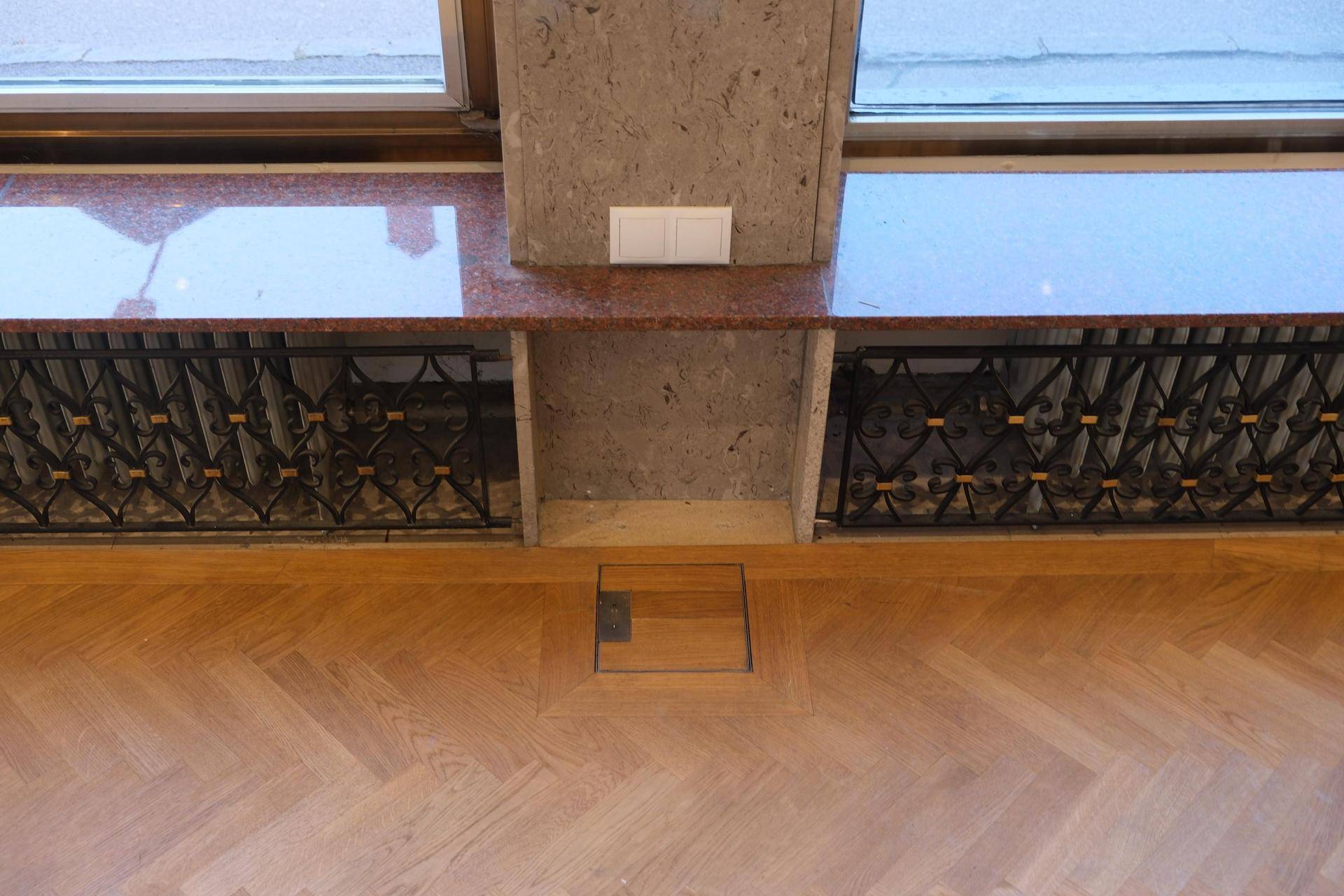 Detailansicht des Fischgrätparketts, der Fensterbank aus Granit und der dekorativen Heizungsverkleidung.
