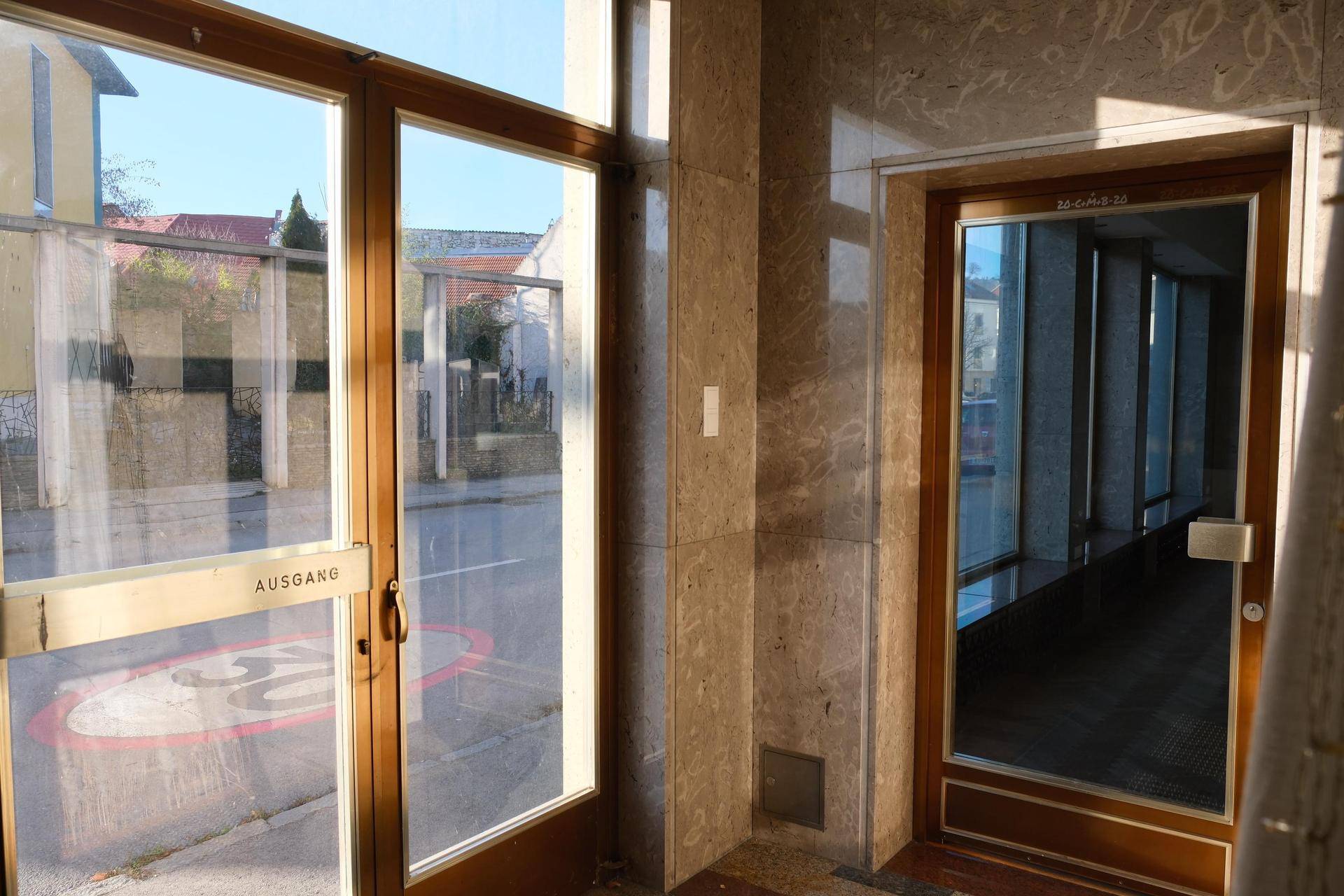Eingangsbereich mit Glastüren, Marmorverkleidung und Blick auf die Straße, der viel Tageslicht hereinlässt.