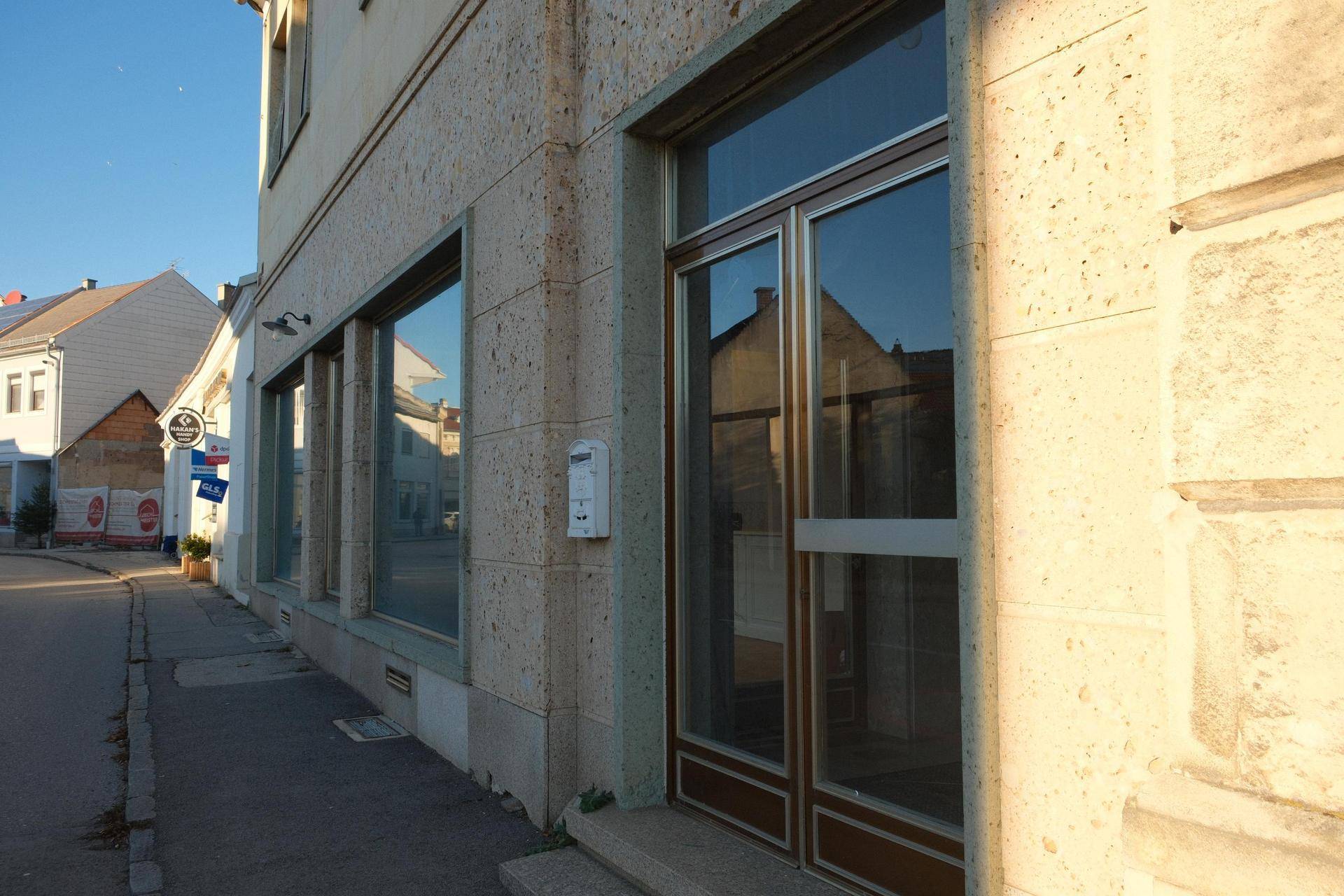 Fassade eines Gebäudes mit großen Fenstern und einem Eingangsbereich, der viel Licht in die Innenräume lässt.
