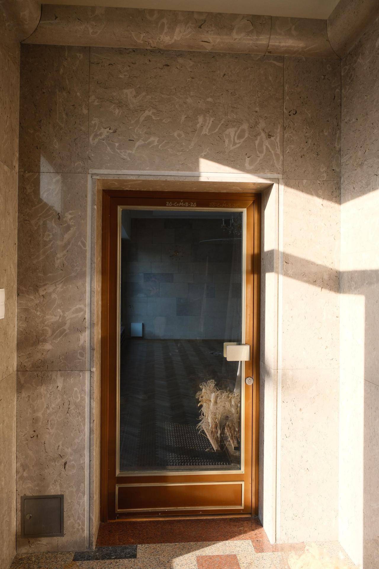 Elegante Holztür mit Glaseinsatz und Marmorverkleidung, die einen stilvollen Übergang zum nächsten Raum bildet.