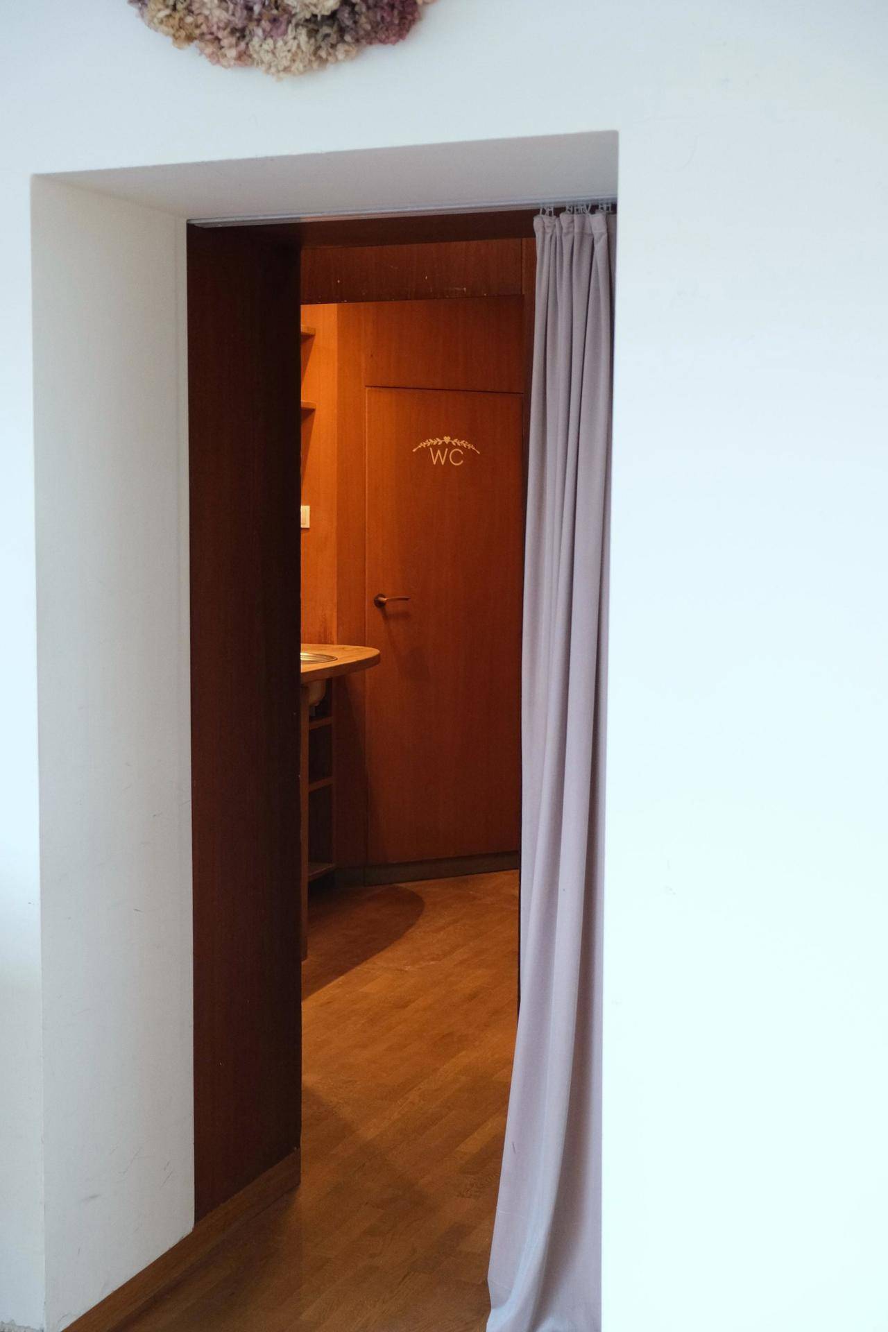 Eingang zu einem Bereich mit Holzeinbauten und einem Waschbecken, der zu einer Toilette führt.