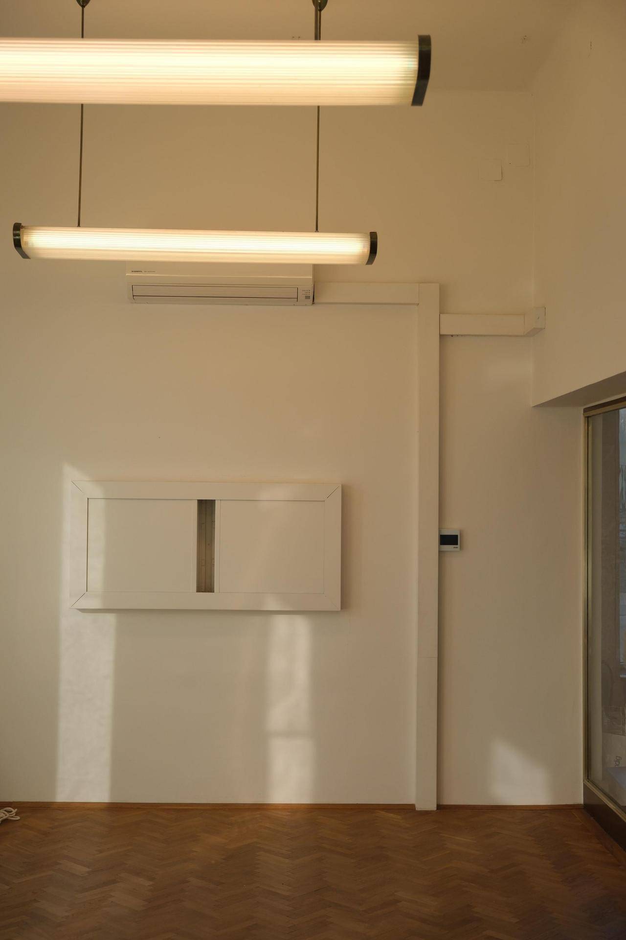 Weiße Wand mit integrierter Klimaanlage und moderner Hängelampe, die den Raum effizient beleuchtet.