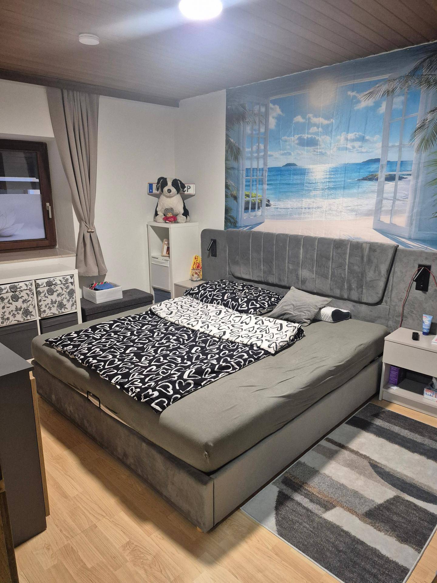 Schlafzimmer mit großem Bett, Holzboden, Holzdecke und dekorativer Wandtapete.