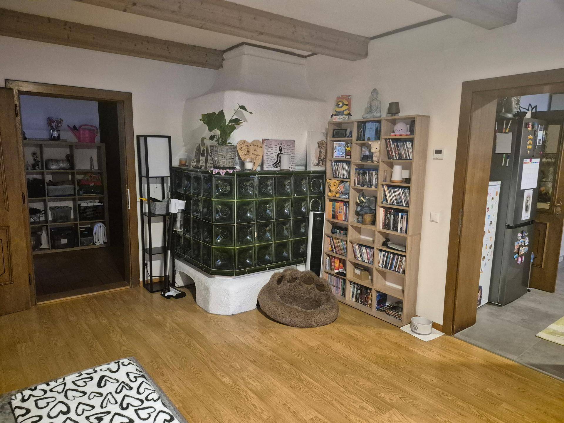 Wohnbereich mit traditionellem Kachelofen, Holzboden und Bücherregalen.