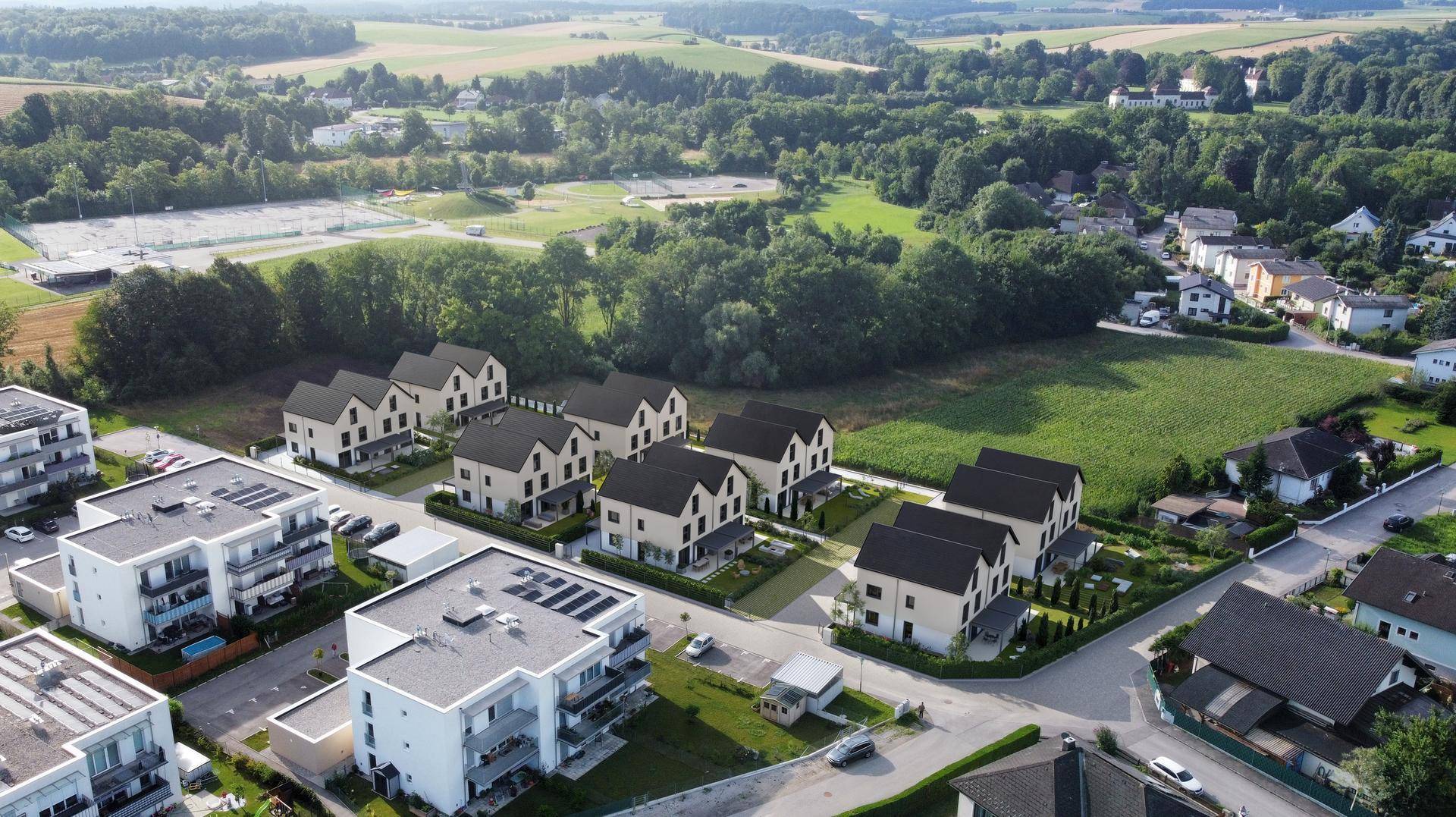 Luftaufnahme einer modernen Wohnsiedlung mit Neubauten, viel Grün und weitem Blick in die Landschaft.
