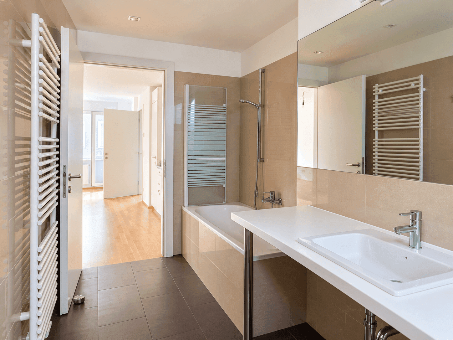 Modernes Badezimmer mit beigefarbenen Fliesen, Badewanne mit Duschwand und beheiztem Handtuchhalter.