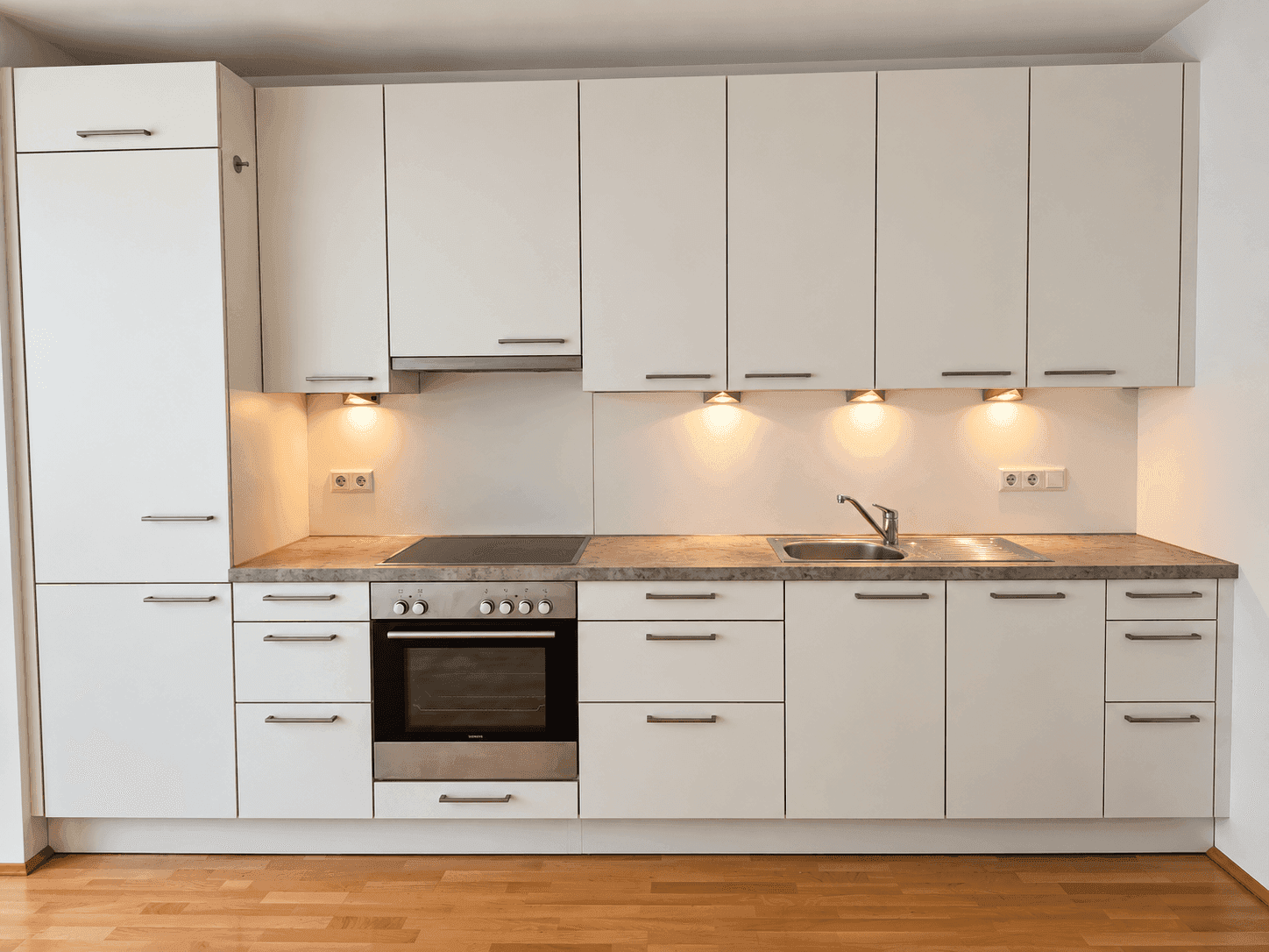 Moderne Einbauküche in Weiß mit integrierten Geräten, Kochfeld und viel Stauraum.