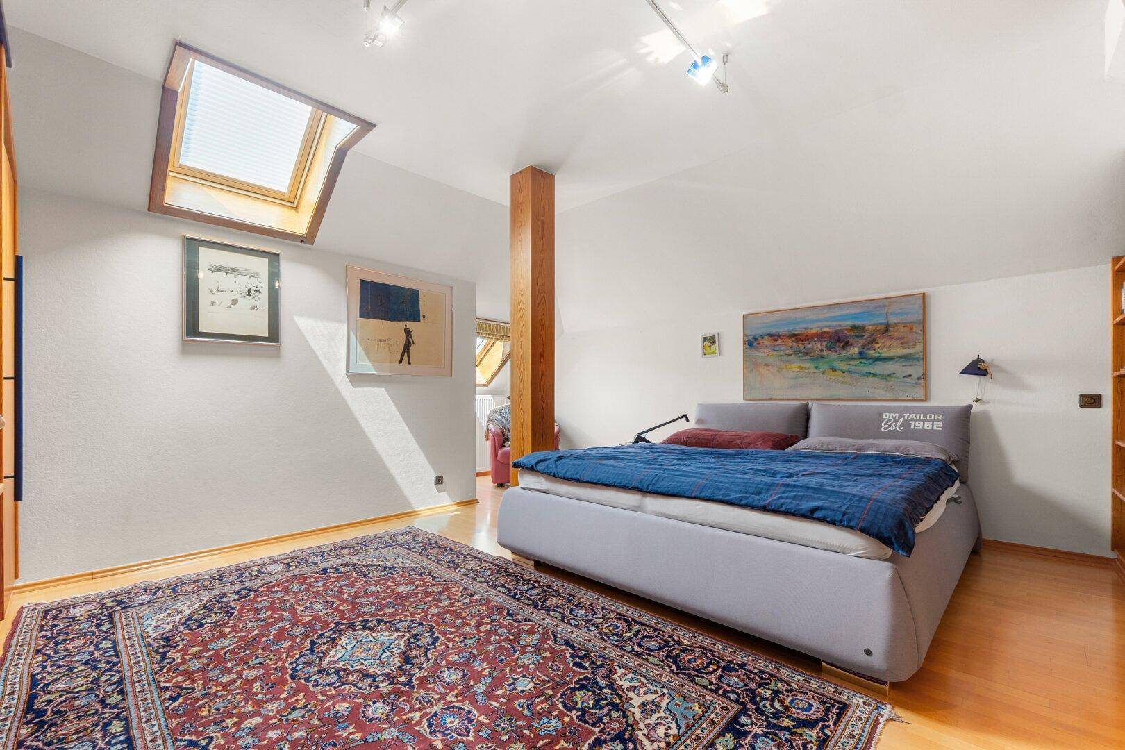Schlafzimmer im Dachgeschoss mit Holzboden, Dachfenster und moderner Einrichtung.