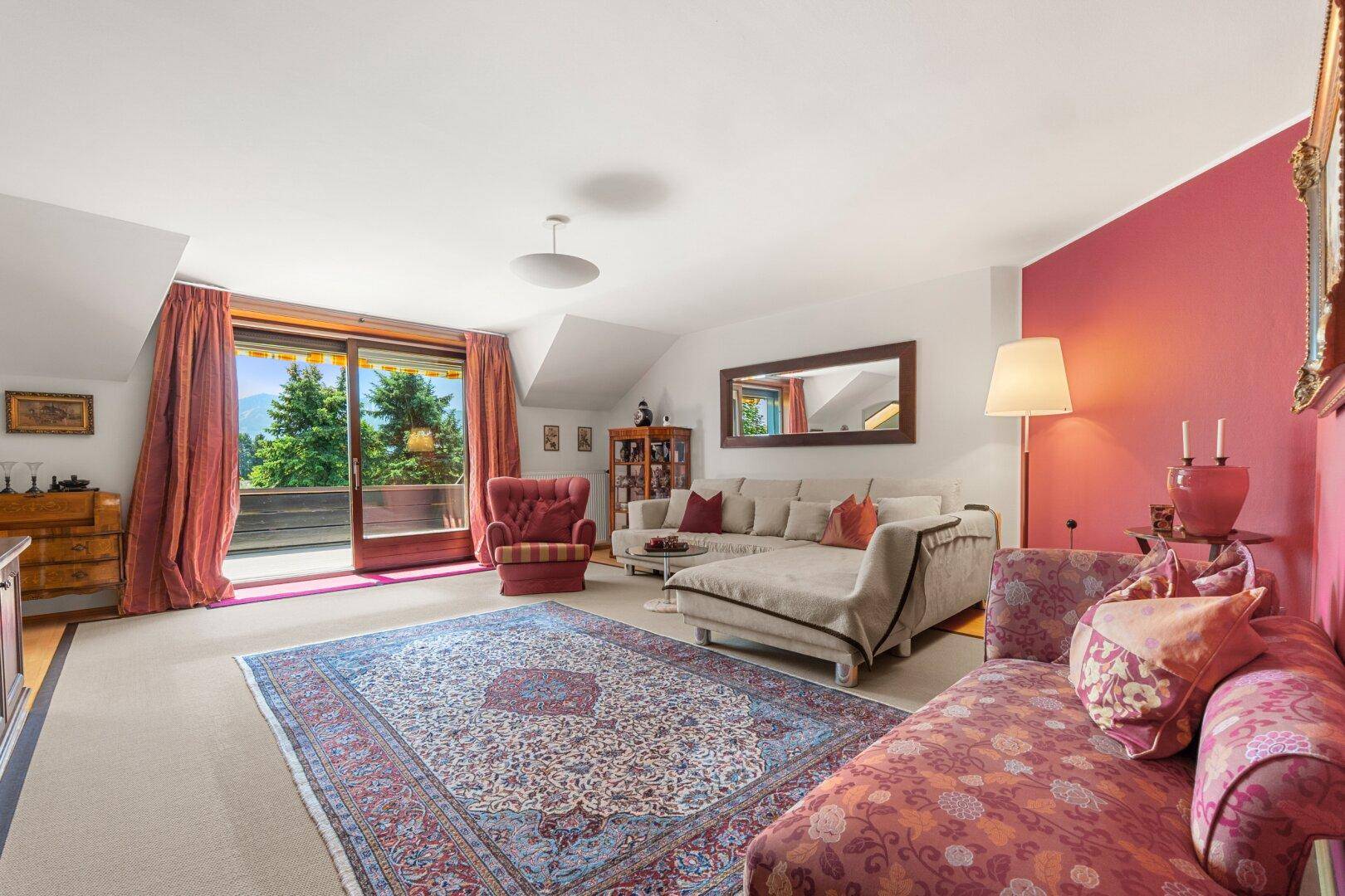 Helles Wohnzimmer im Dachgeschoss mit Zugang zum Balkon und farbenfroher Dekoration.