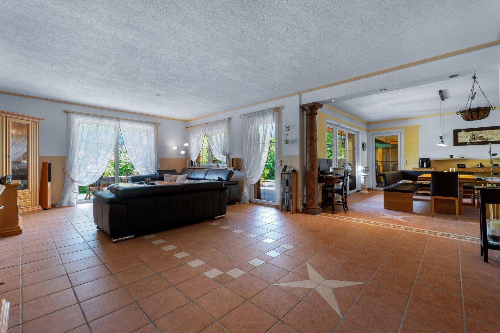 Geräumiger offener Wohn- und Essbereich mit Terrakotta-Fliesenboden und Zugang zur Terrasse.