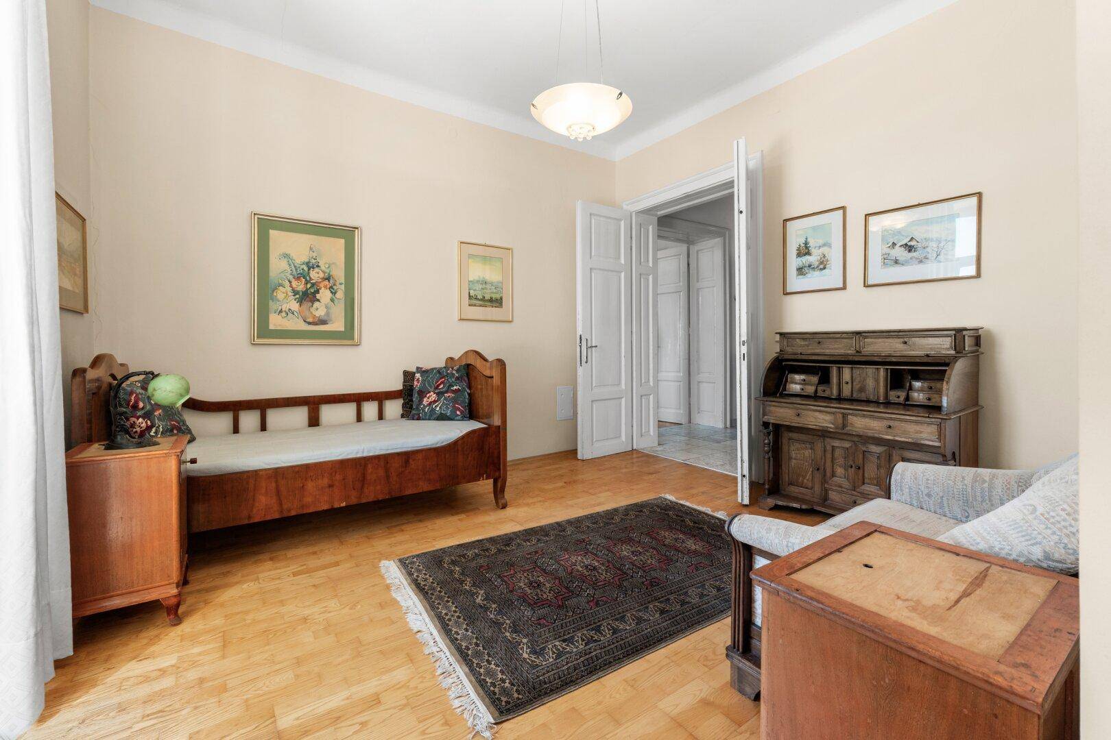 Gemütliches Schlafzimmer mit Holzbett, antikem Schreibtisch und Parkettboden.