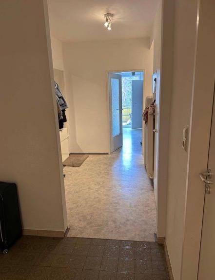 Langer Flur mit unterschiedlichen Bodenbelägen, der zu weiteren Räumen der Wohnung führt.