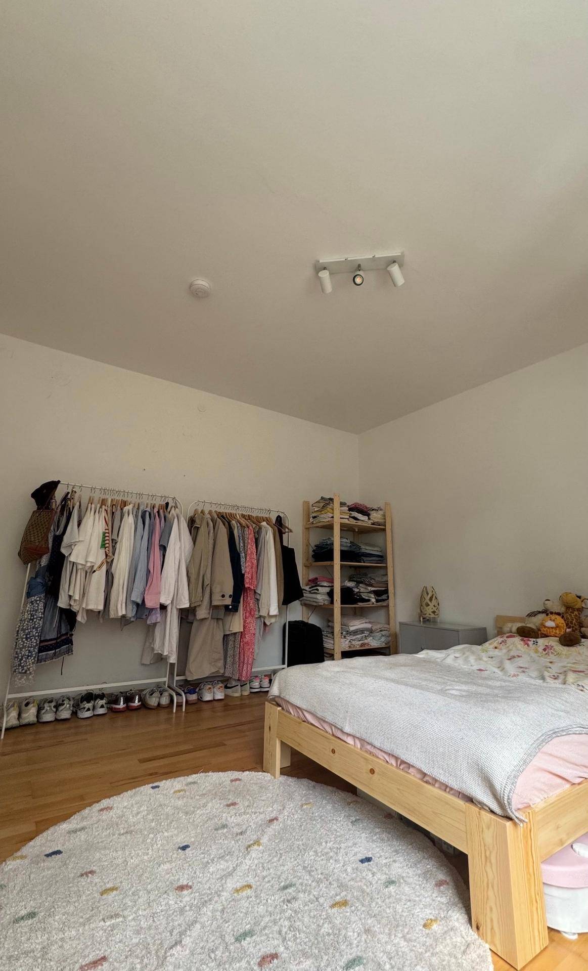 Schlafzimmer mit Kleiderstange, Holzregal und Holzboden, bietet Stauraum und Funktionalität.