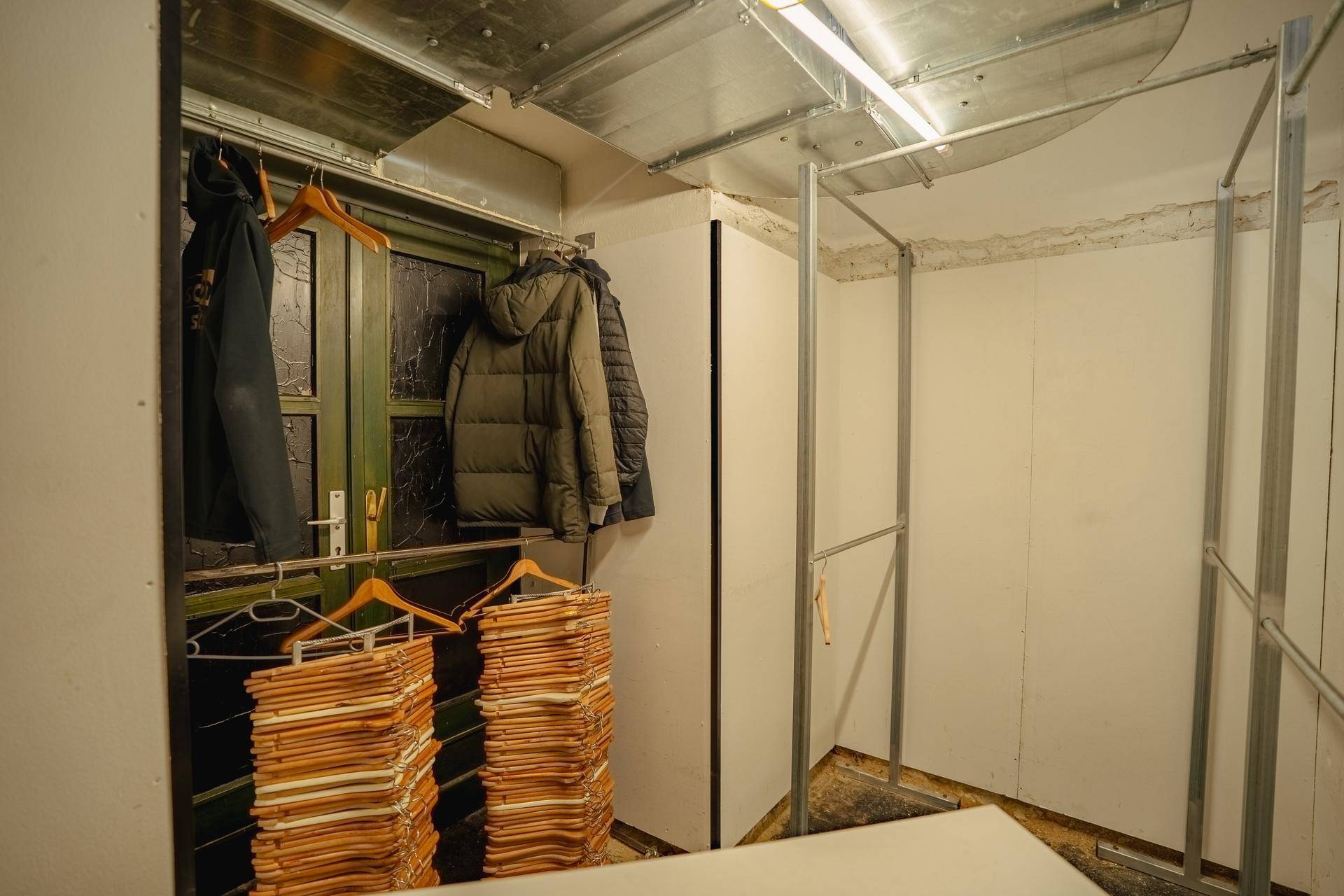 Garderobenbereich mit Kleiderbügeln und Metallkonstruktionen, bereit für die Aufbewahrung von Jacken der Gäste.