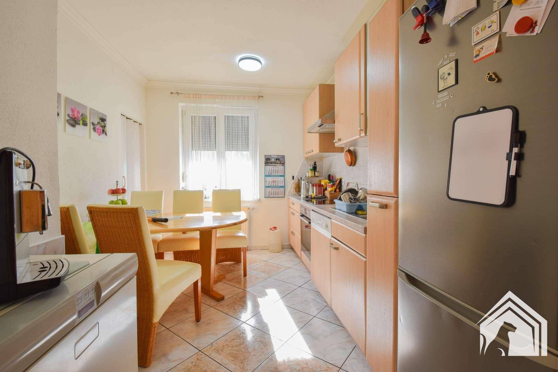 Helle Wohnküche mit Esstisch, Holzschränken und großem Kühlschrank, ideal für Familien.