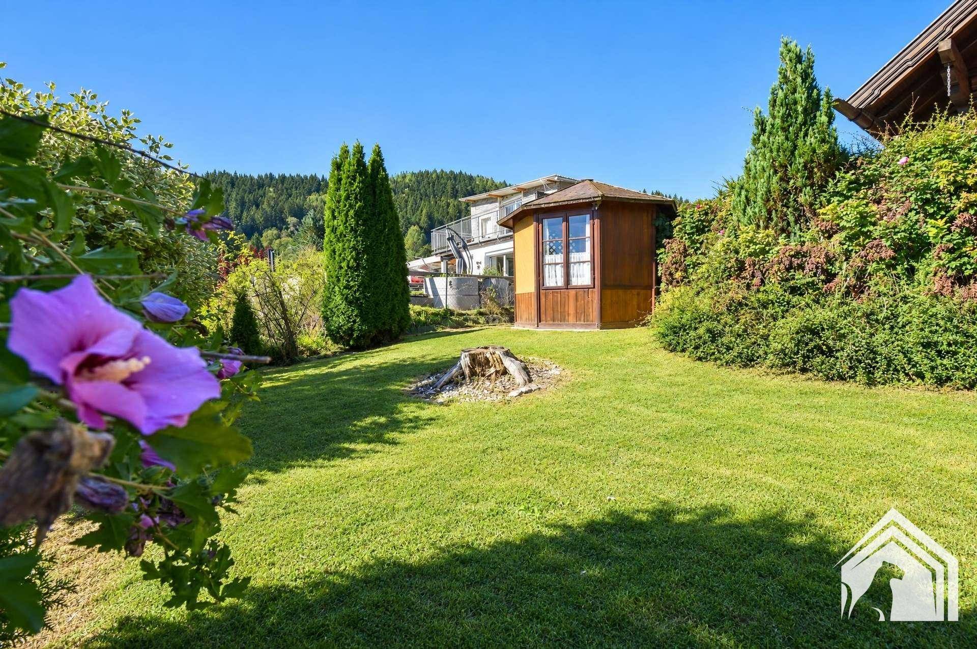 Gepflegter Gartenbereich mit Rasen, Blumen und einem charmanten Holzpavillon.
