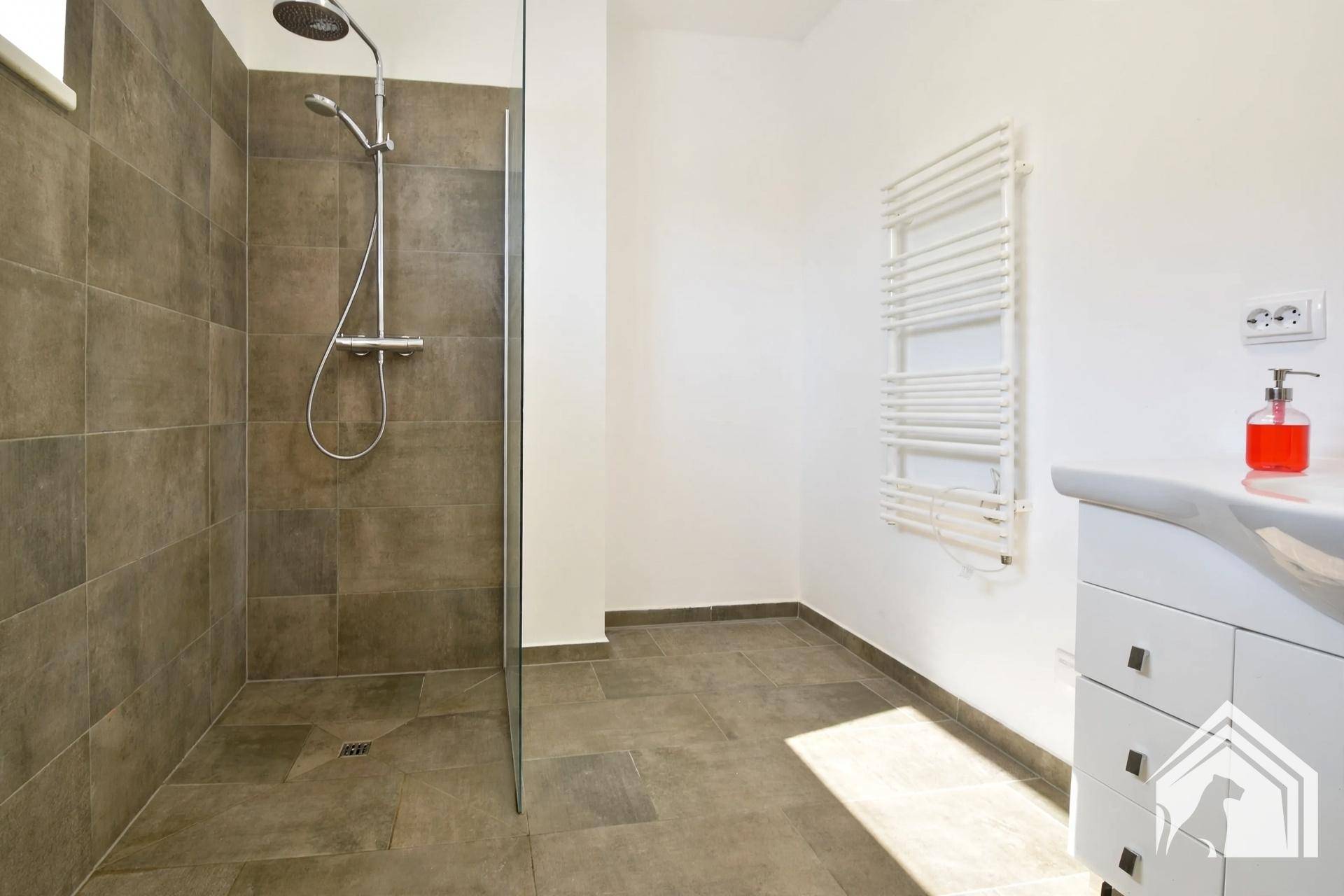 Modernes Badezimmer mit ebenerdiger Dusche, großen Fliesen und beheiztem Handtuchhalter.