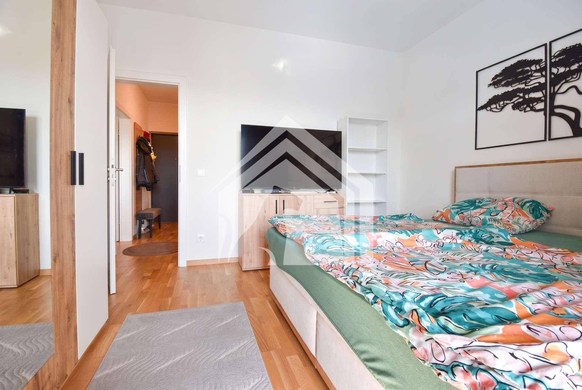 Schlafzimmer mit Holzboden, Doppelbett und einem Fernseher, der für Unterhaltung sorgt.
