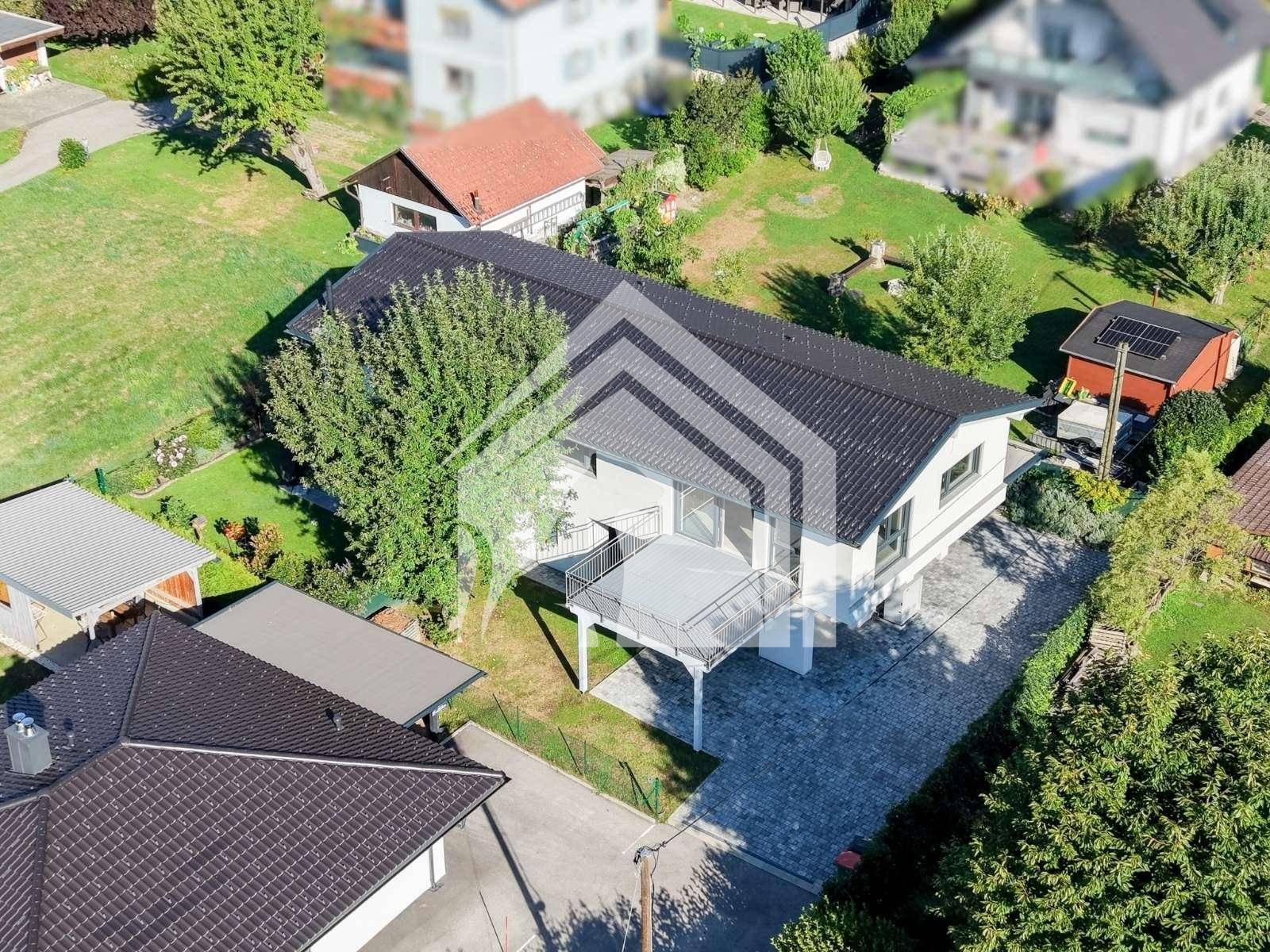 Luftaufnahme des modernen Hauses mit großem Balkon und gepflegtem Grundstück in grüner Umgebung.