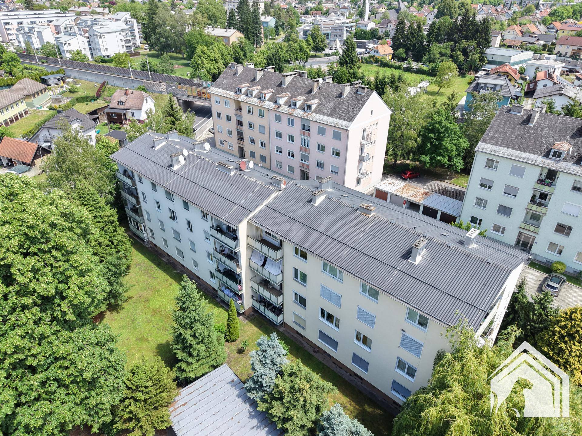 Luftaufnahme des Wohnkomplexes mit Balkonen, umgeben von Bäumen und Grünflächen.