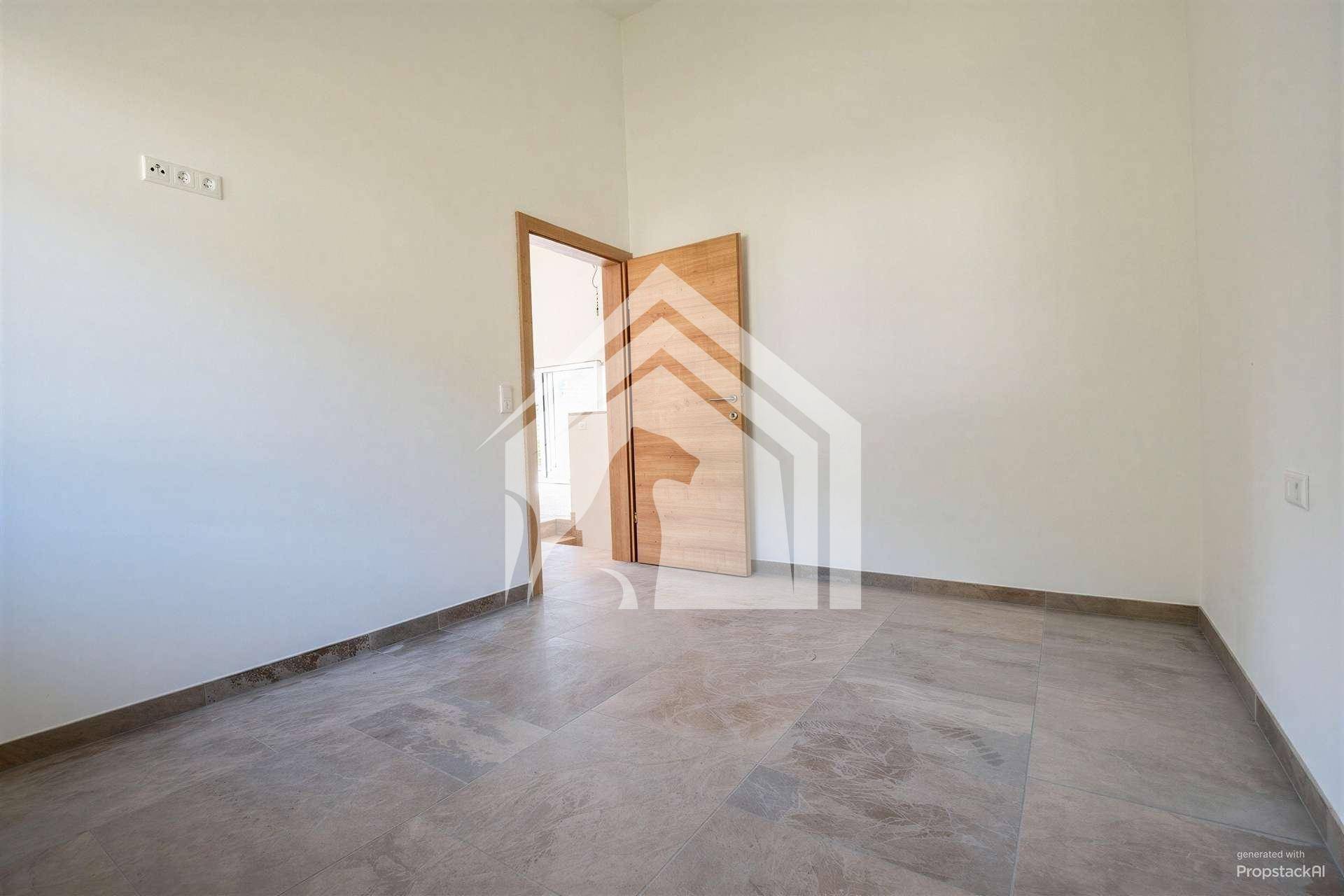 Geräumiger, heller Raum mit Fliesenboden und Holztür, ideal für Schlaf- oder Arbeitszimmer.