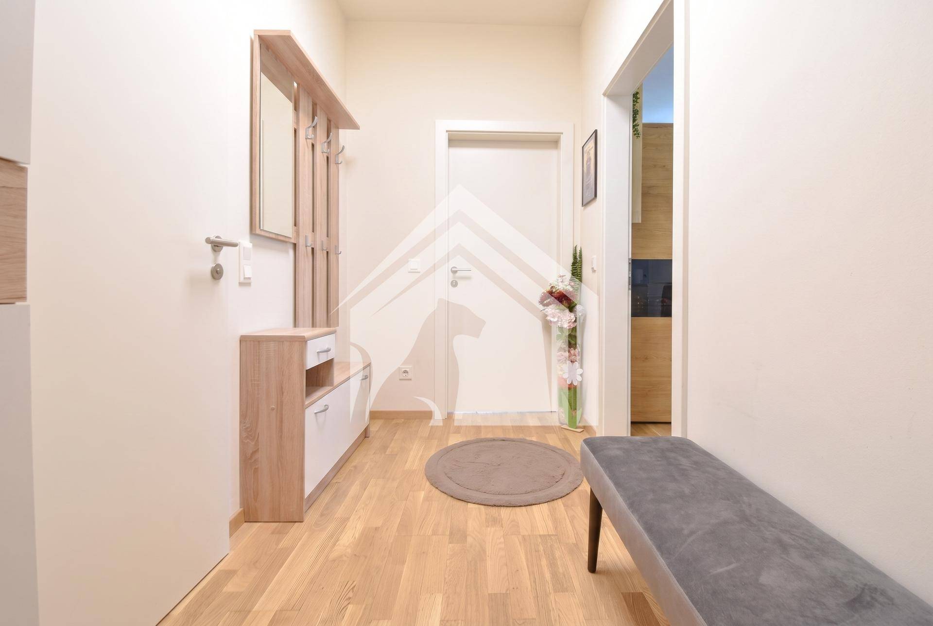 Heller Flur mit Holzboden, Garderobe und einem Spiegel, der den Eingangsbereich erweitert.