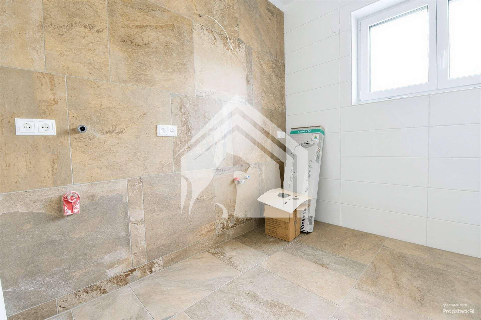Badezimmer in Vorbereitung mit Fliesenboden, Fenster und Anschlüssen für Sanitäreinrichtungen.