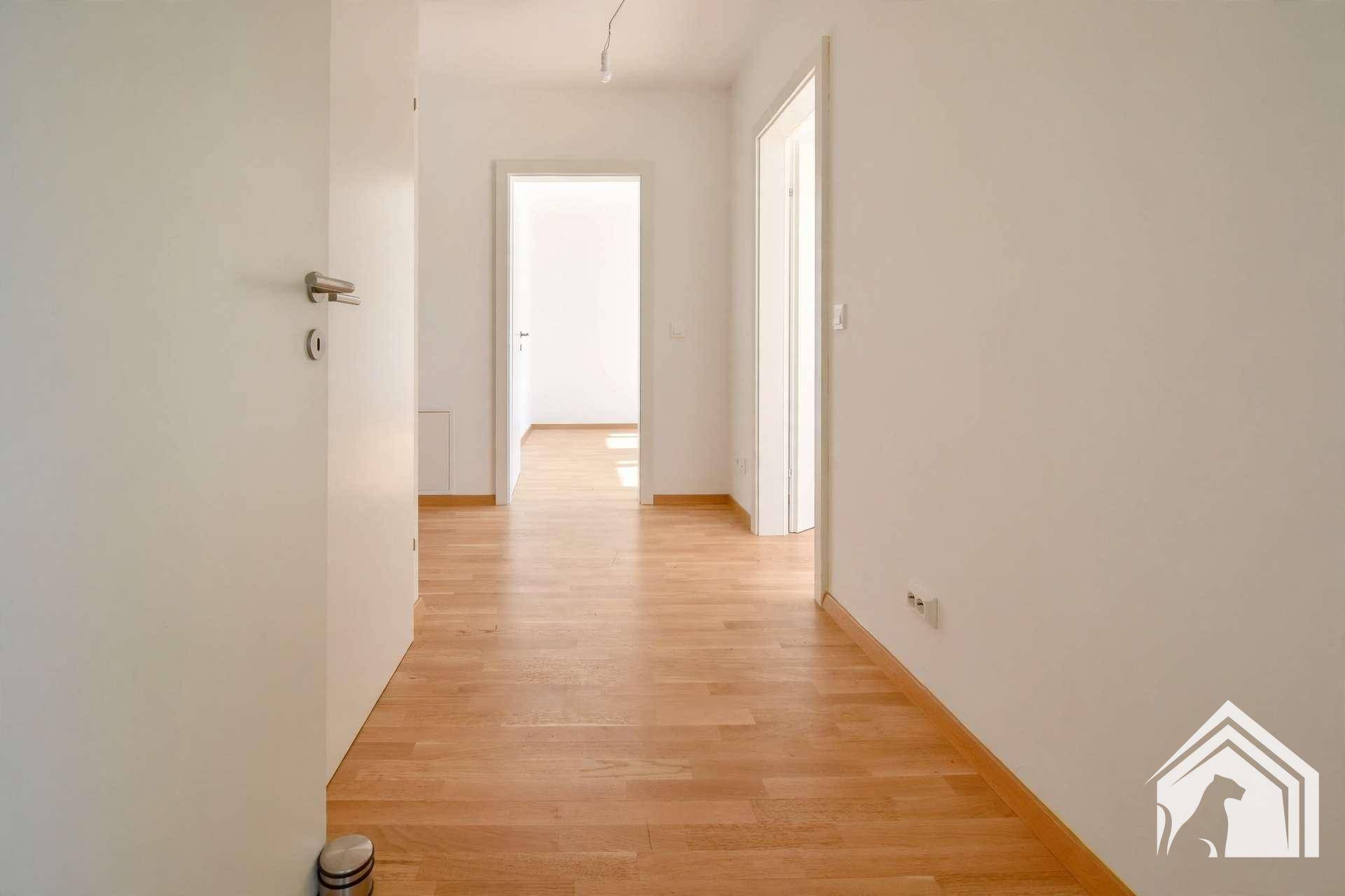Langer, heller Flur mit Holzboden und Türen zu den angrenzenden Zimmern.