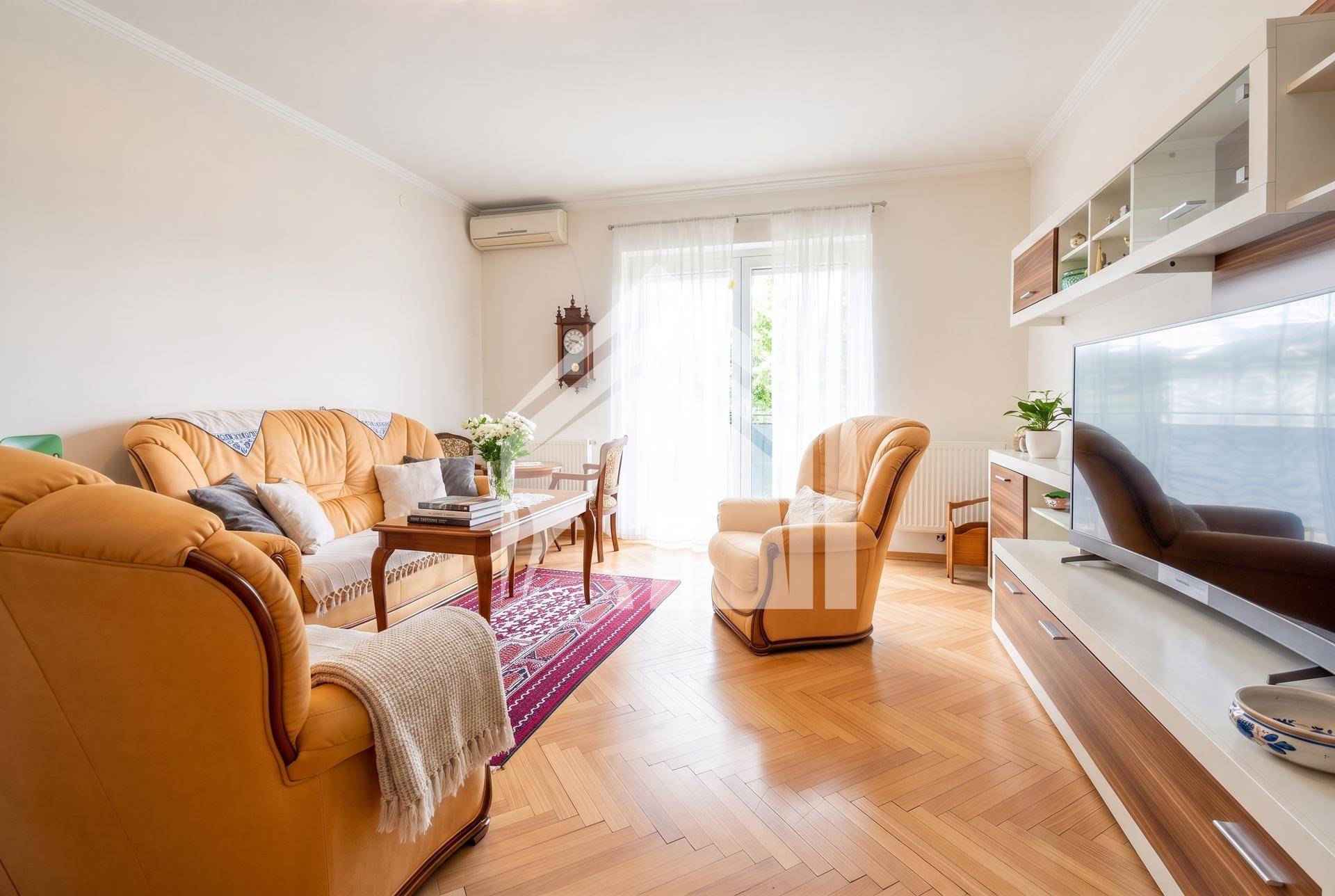 Gemütliches Wohnzimmer mit traditionellen Möbeln, Fischgrätparkett und Zugang zum Balkon.