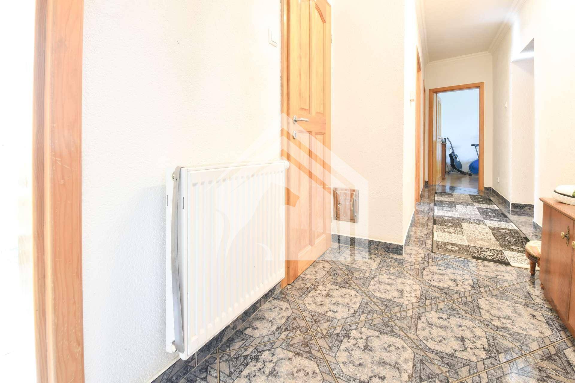 Flur mit gemusterten Fliesenboden und einem Heizkörper an der Wand.
