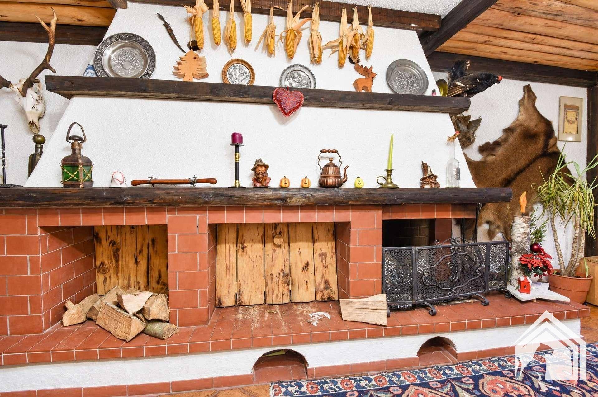 Großer gemauerter Kamin mit Holzscheiten und traditioneller Dekoration im Wohnbereich.