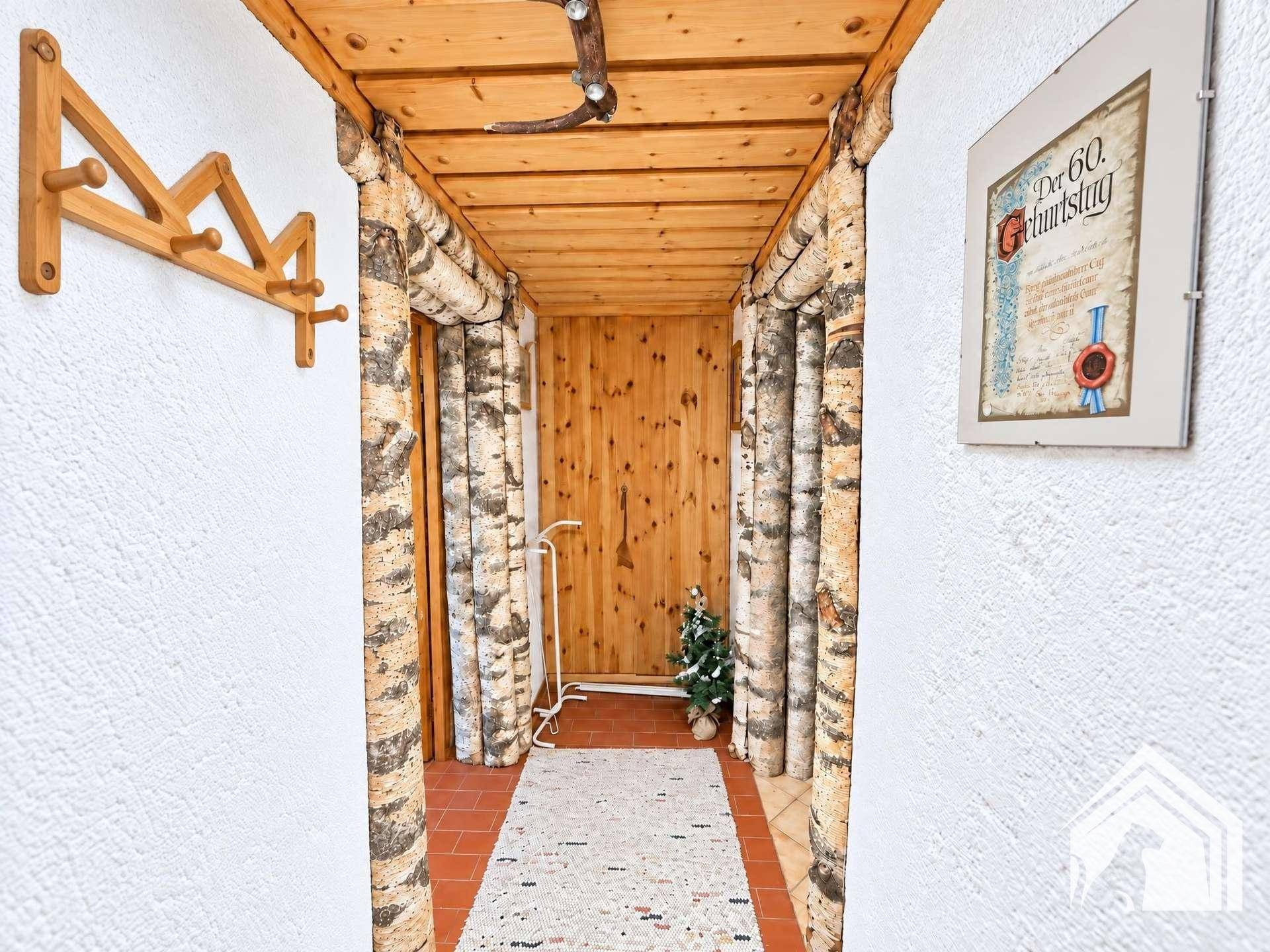 Einzigartiger Flur mit Birkenstamm-Dekoration, Holzwänden und Fliesenboden.