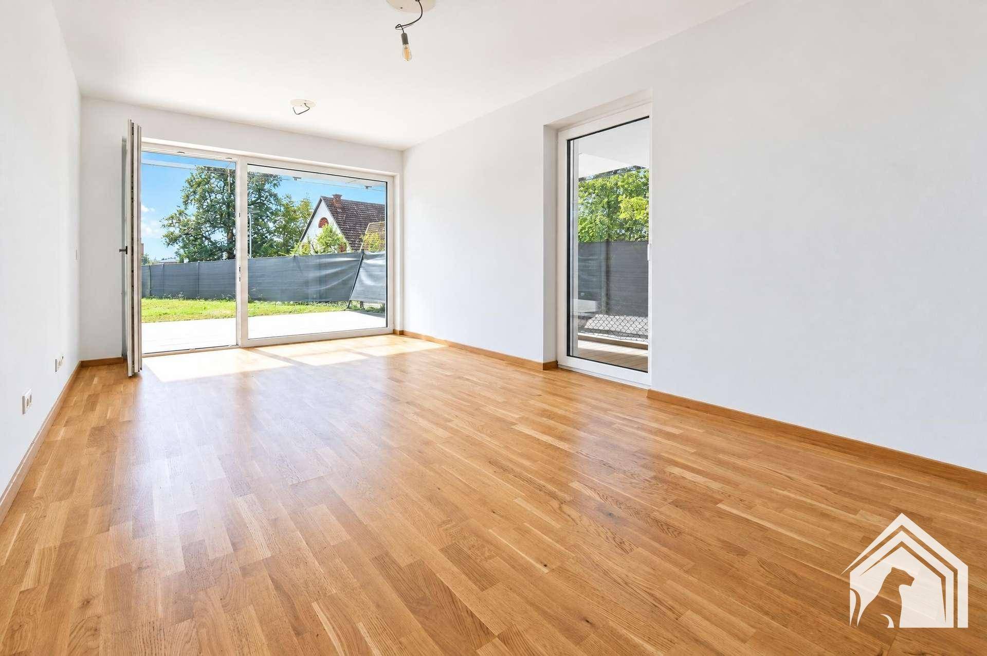 Geräumiges Wohnzimmer mit hellem Parkettboden und direktem Zugang zur Terrasse und zum Garten.